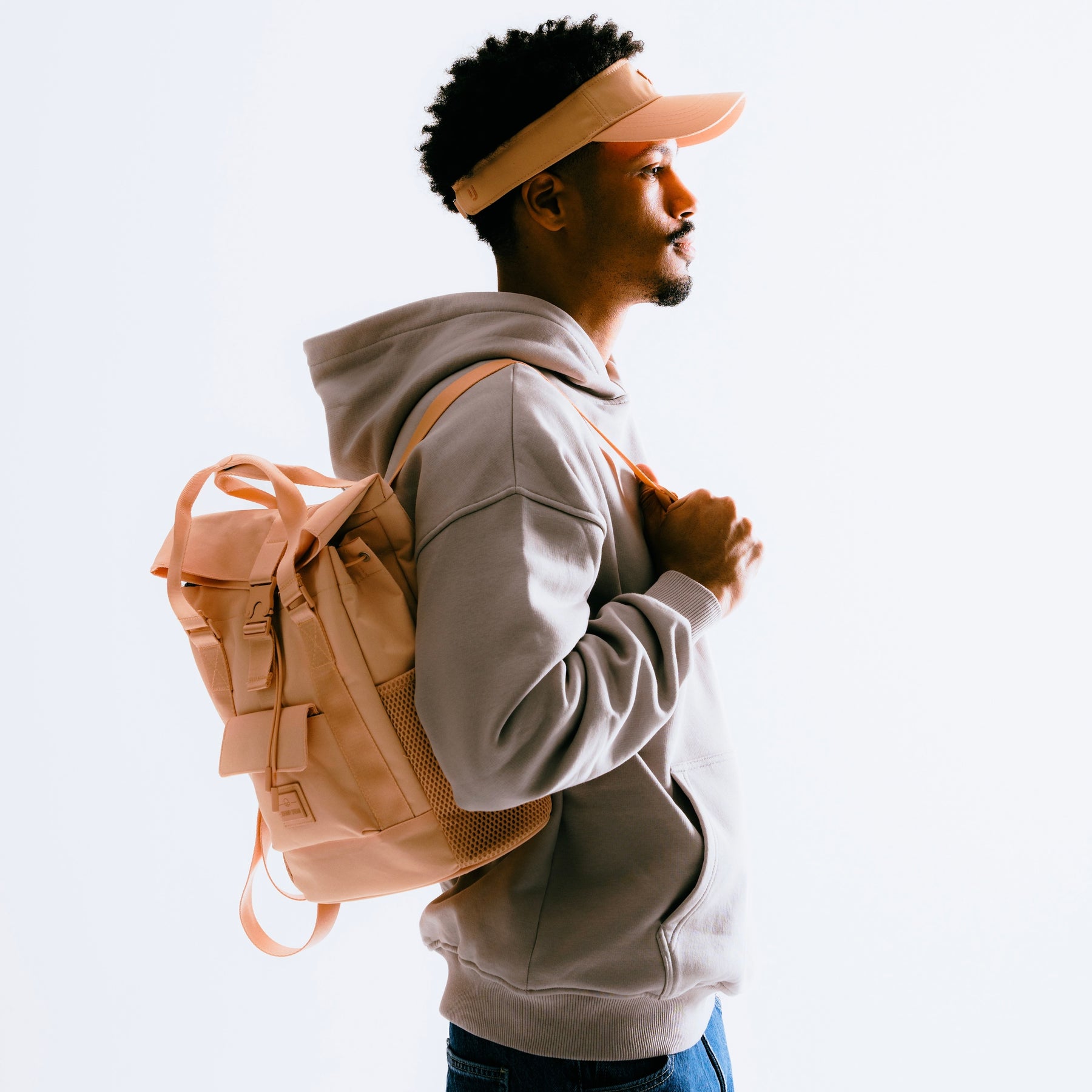 Mann in grauem Hoodie und Cap trägt peachfarbenen Tagesrucksack 'Jules' von Johnny Urban auf Schultern