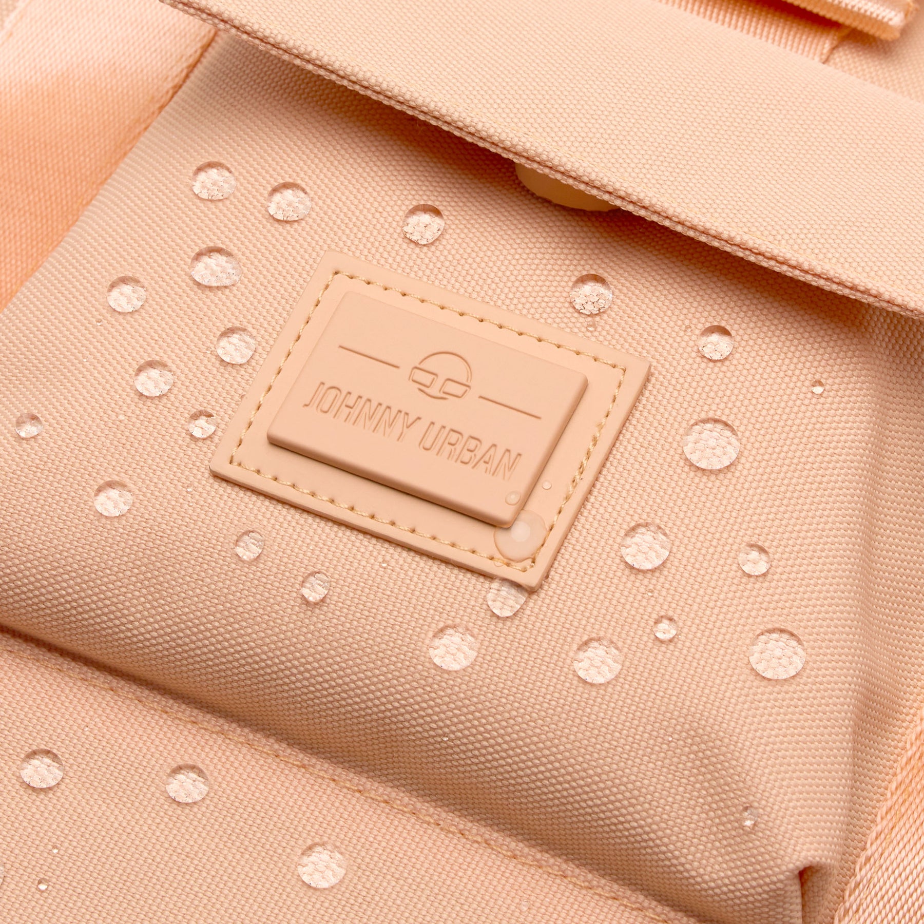 Nahaufnahme des peachfarbenen, wasserabweisenden Rucksacks 'Jules' von Johnny Urban mit Logo-Patch