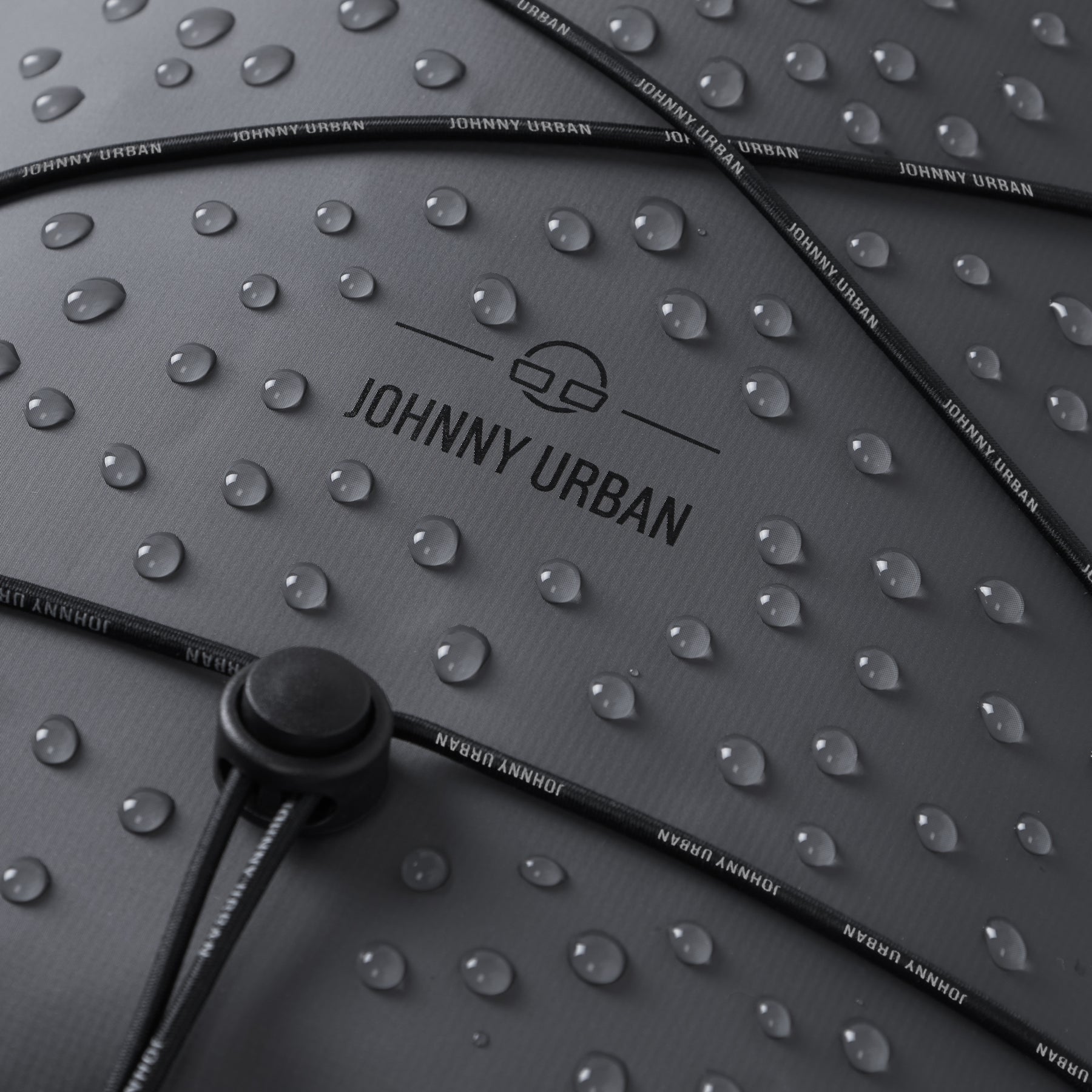 Wasserabweisende Oberfläche des grauen Rolltop Rucksacks 'Myles' von Johnny Urban mit Wassertropfen und verstellbarem Kordelzug