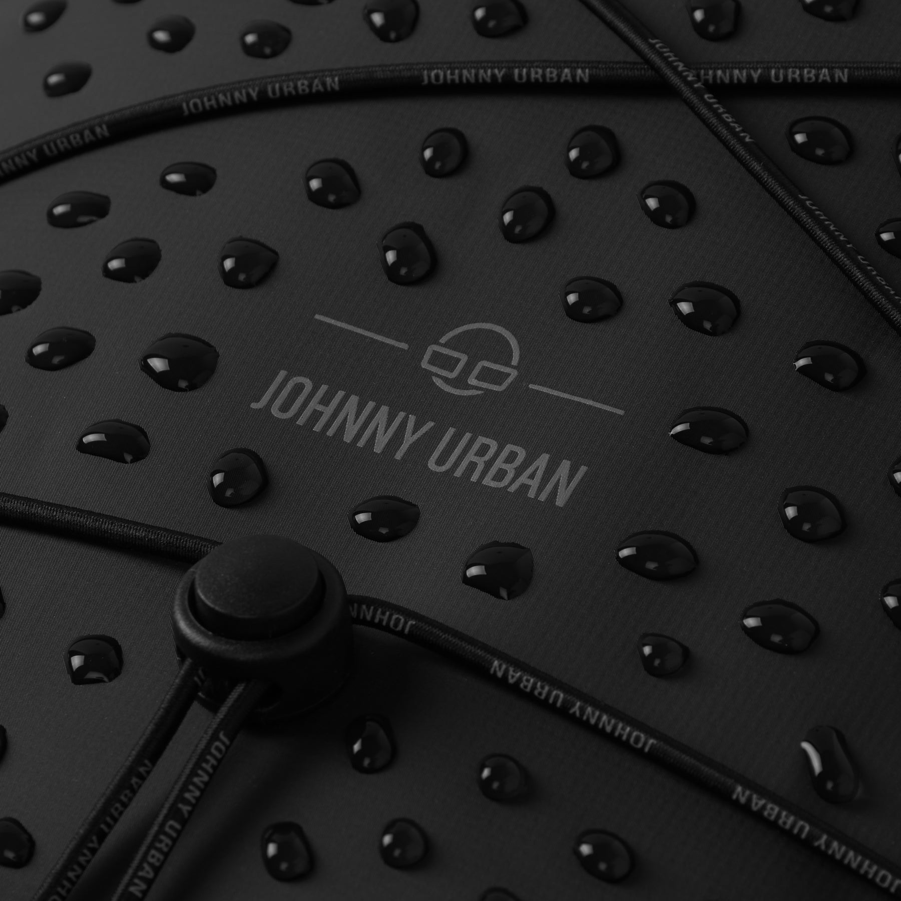 Wasserabweisende Oberfläche eines schwarzen Johnny Urban Rolltop Rucksacks 'Myles' mit Wassertropfen