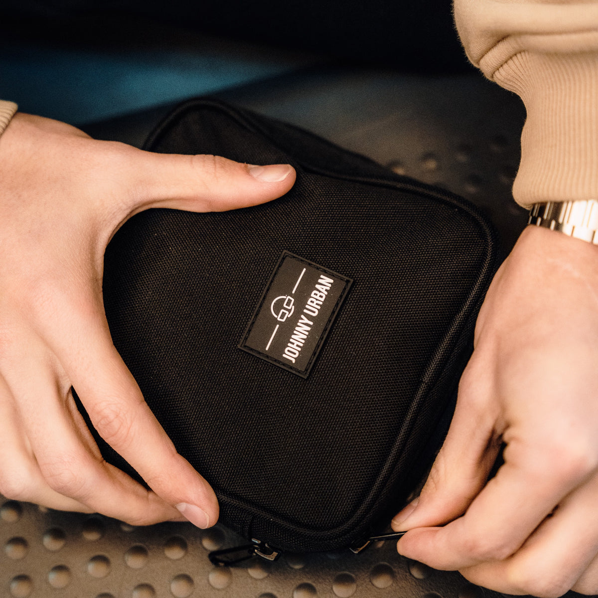 Schwarzer Tech Organizer 'Ted' von Johnny Urban in rechteckiger Form aus robustem Material, gehalten von zwei Händen