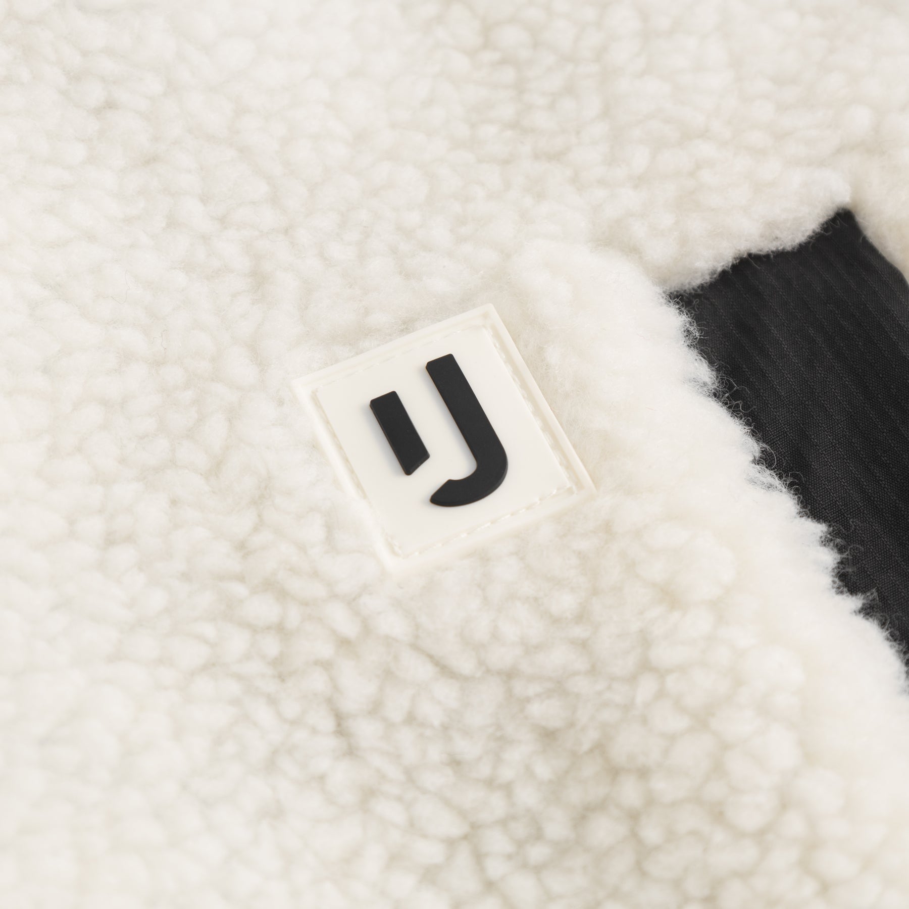 Nahe Aufnahme des weißen Teddy-Fleece-Stoffs der Fleecejacke "Carson" mit Johnny Urban Logo