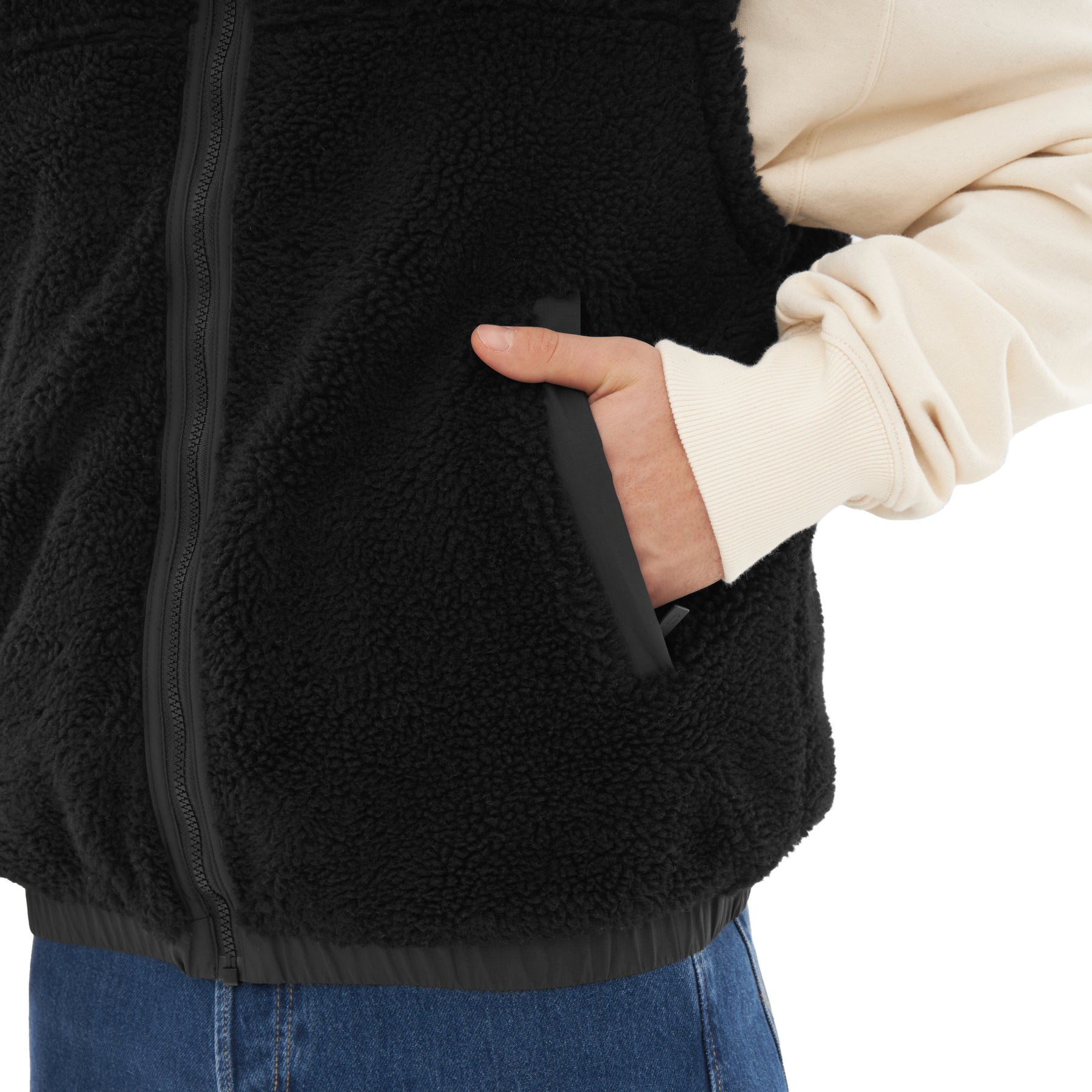 Schwarze Teddy Fleeceweste 'Bryson' mit Reißverschluss und Hand in Seitentasche, beige Pullover unter der Weste