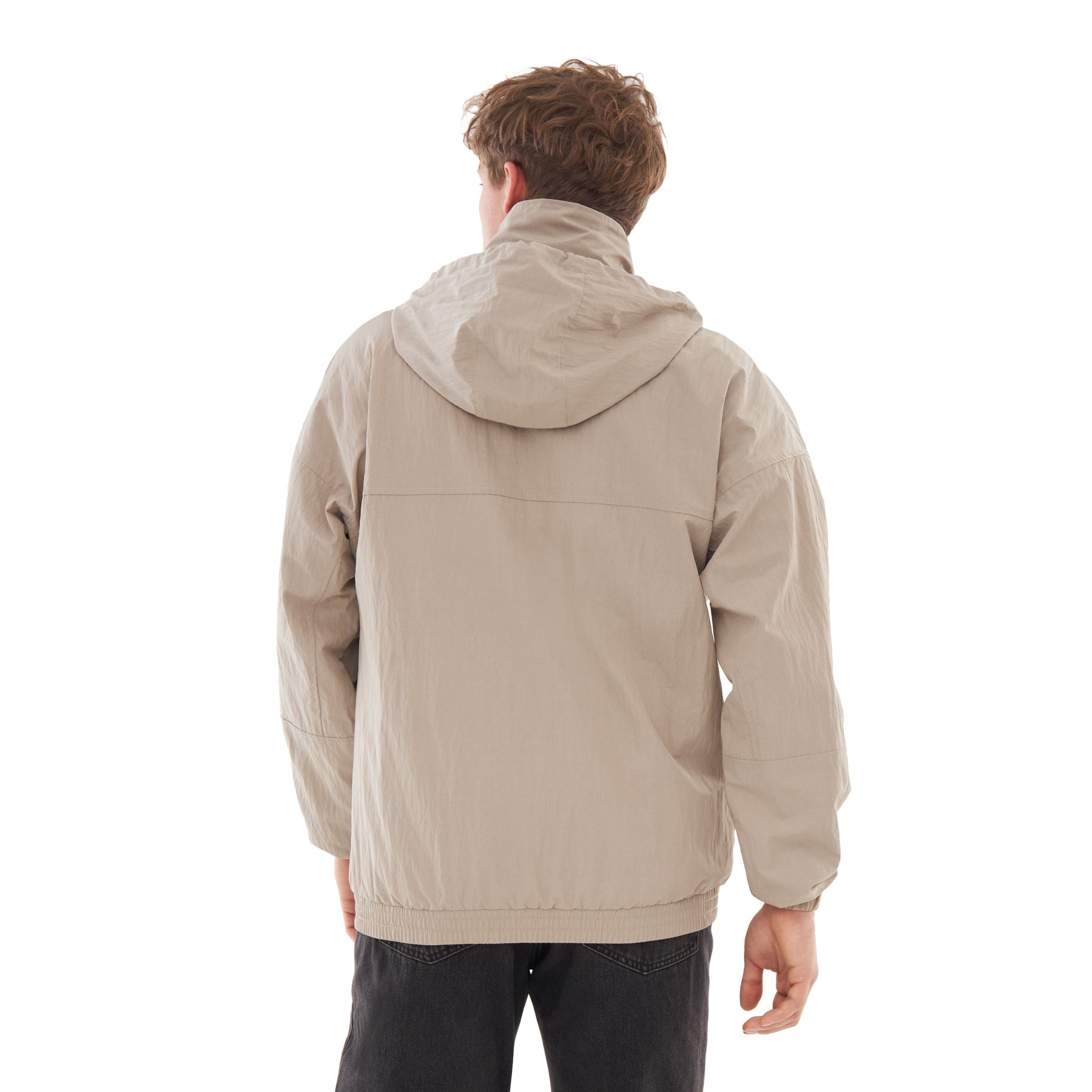 Rückansicht einer Person mit beige Übergangsjacke 'Lennon' und Kapuze, trägt schwarze Hose