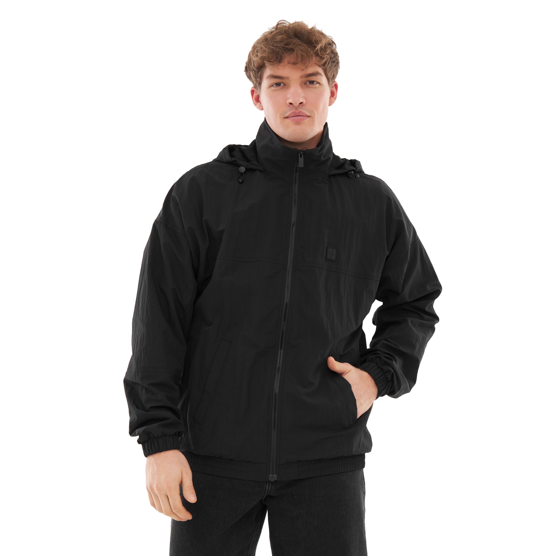 Mann trägt schwarze Übergangsjacke 'Lennon' mit Reißverschluss und Kapuze, eine Hand in der Tasche
