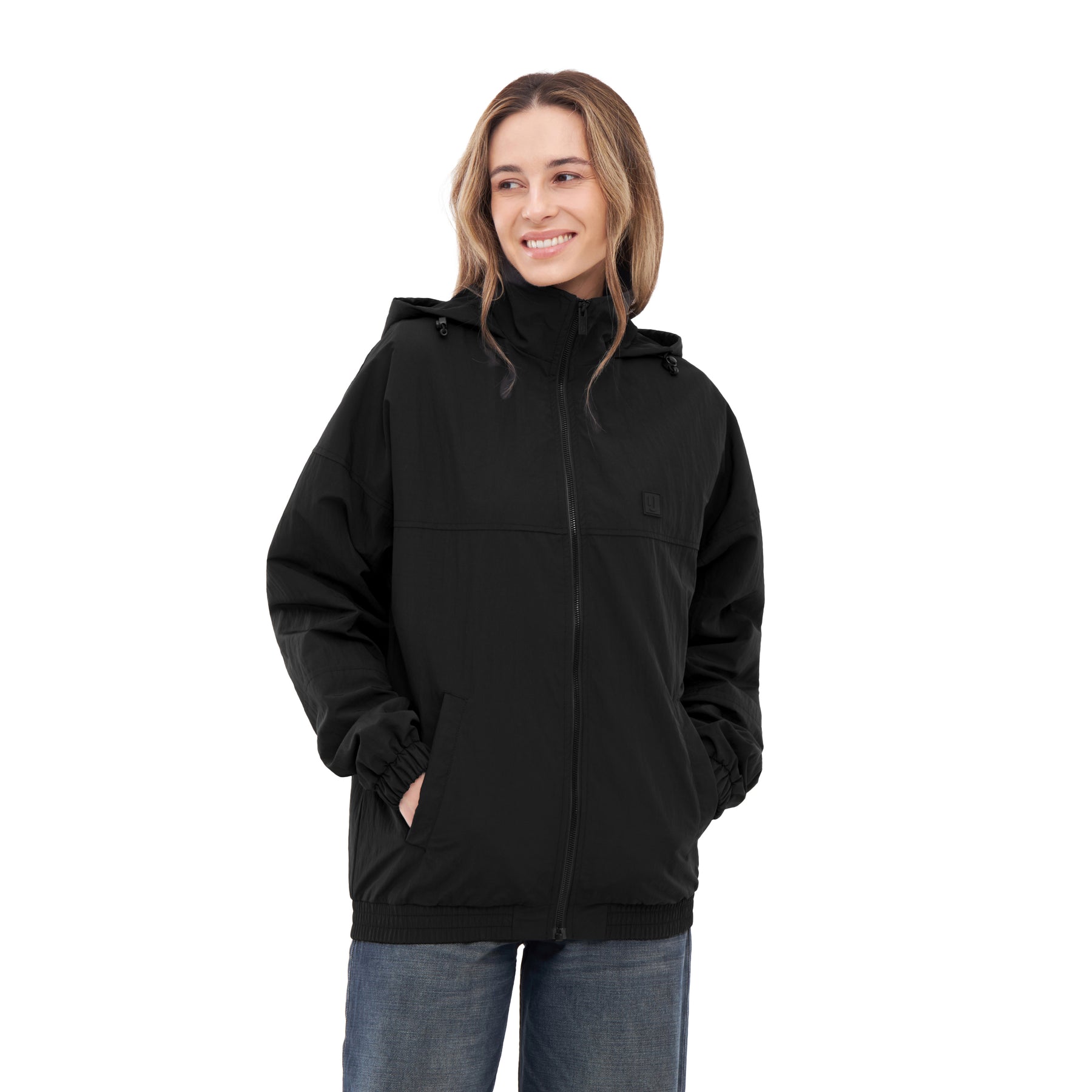 Frau trägt schwarze Übergangsjacke 'Lennon' mit Kapuze und Reißverschluss, Hände in Taschen, lächelt