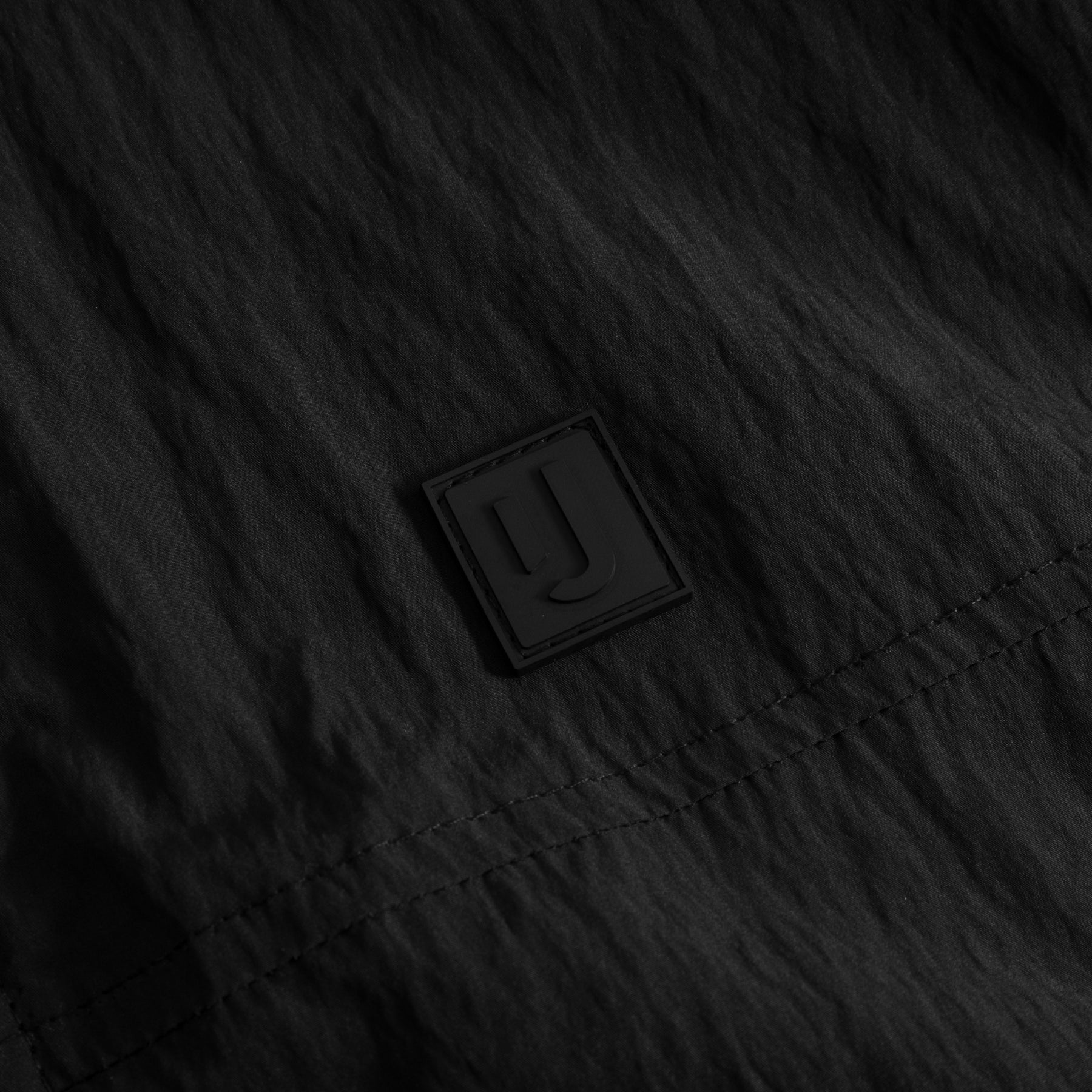 Schwarzes Material mit feiner Textur und genähtem Saum der Übergangsjacke 'Lennon' mit Johnny Urban Logo