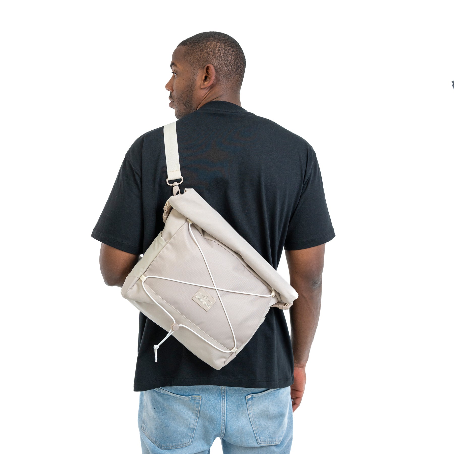 Mann von hinten mit schwarzem T-Shirt und blauer Jeans, trägt beige Umhängetasche 'Dylan' von Johnny Urban über eine Schulter