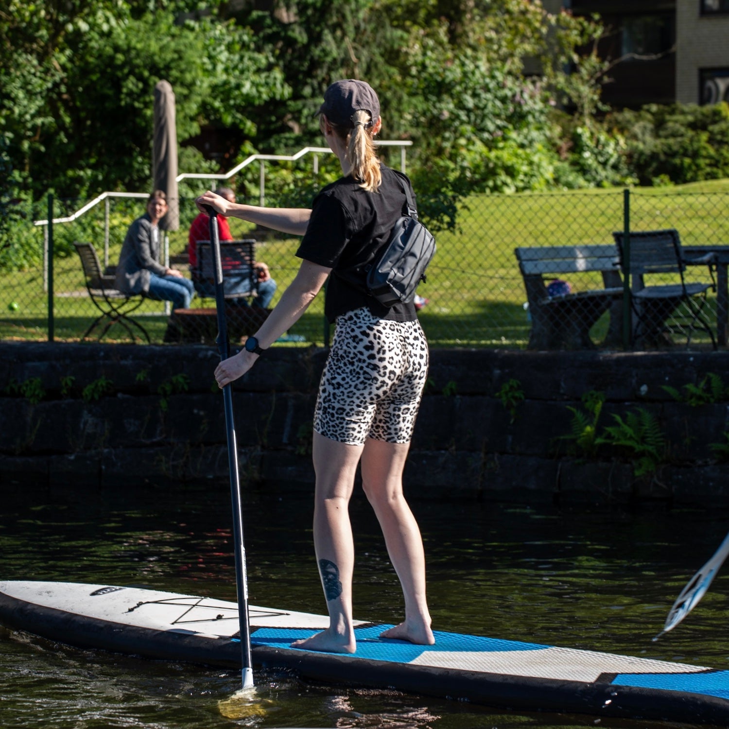 Frau auf Paddleboard mit schwarzer Lenkertasche Fahrrad 'Arlo' am Körper beim Paddeln
