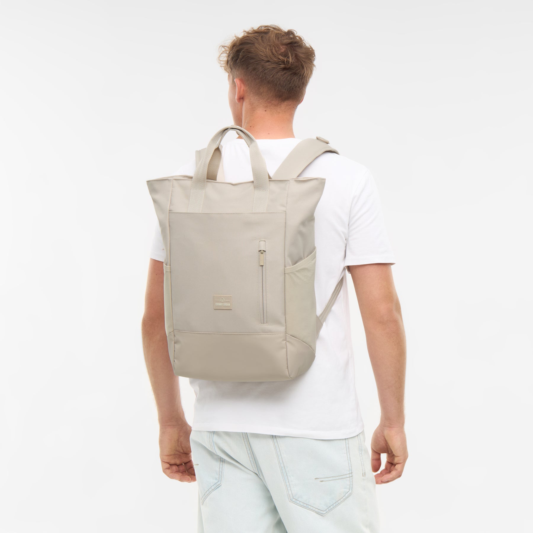 Mann trägt sandfarbene Wickeltasche 'Blair' als Rucksack, Rückansicht