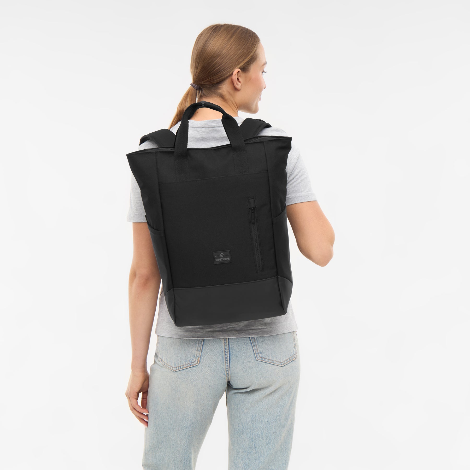 Frau von hinten mit schwarzer Wickeltasche 'Blair' von Johnny Urban, graues T-Shirt, helle Jeans