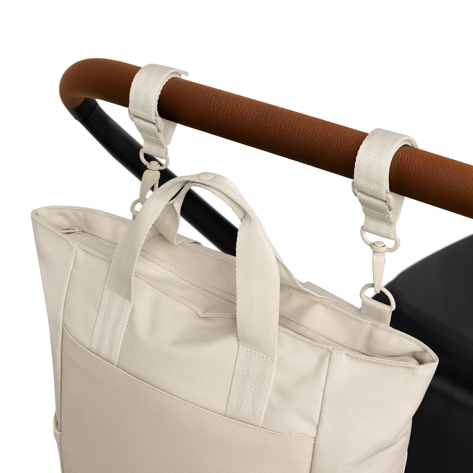 Wickeltasche 'Blair' in Beige, befestigt am braunen Griff eines Kinderwagens mit zwei Haken