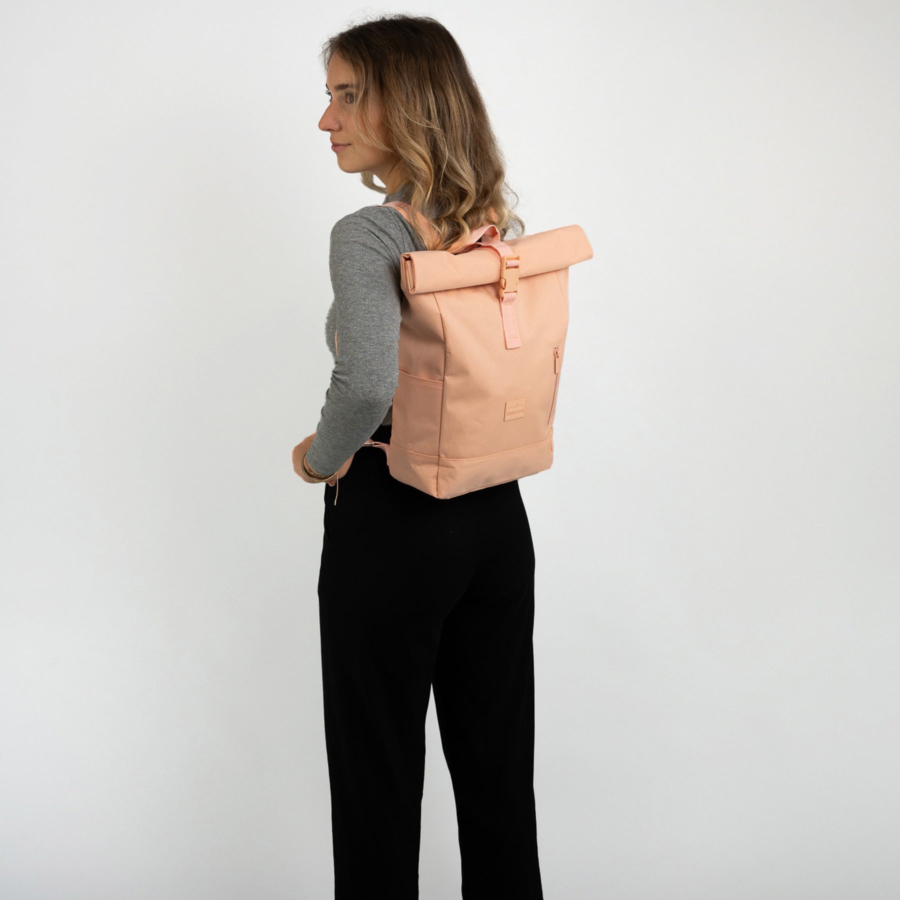 Frau trägt Johnny Urban Rolltop Rucksack 'Robin Small' in Pfirsichfarbe