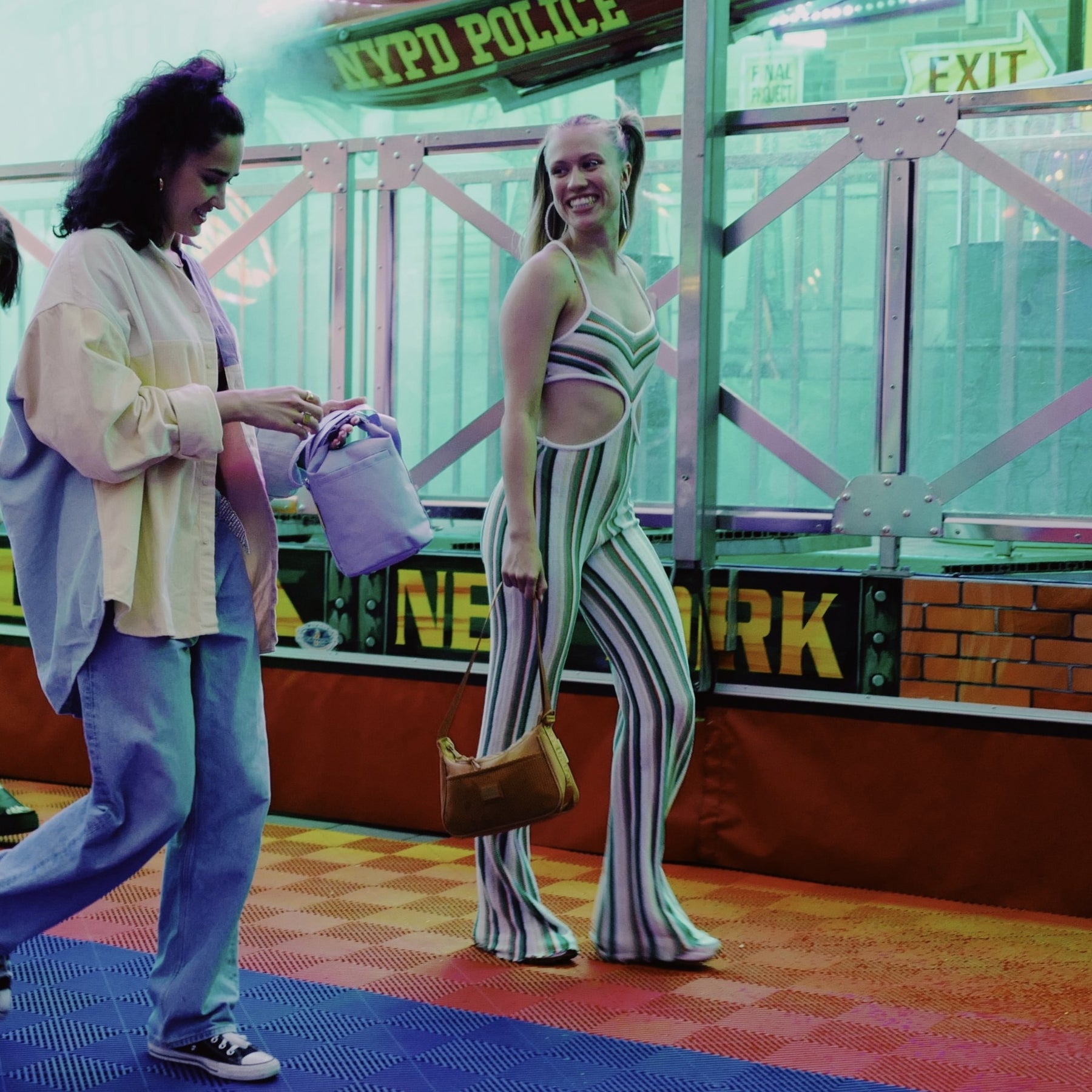 Zwei Frauen gehen nebeneinander, eine trägt Handtasche 'Maddy' in karamellbraun, die andere eine lilafarbene Tasche