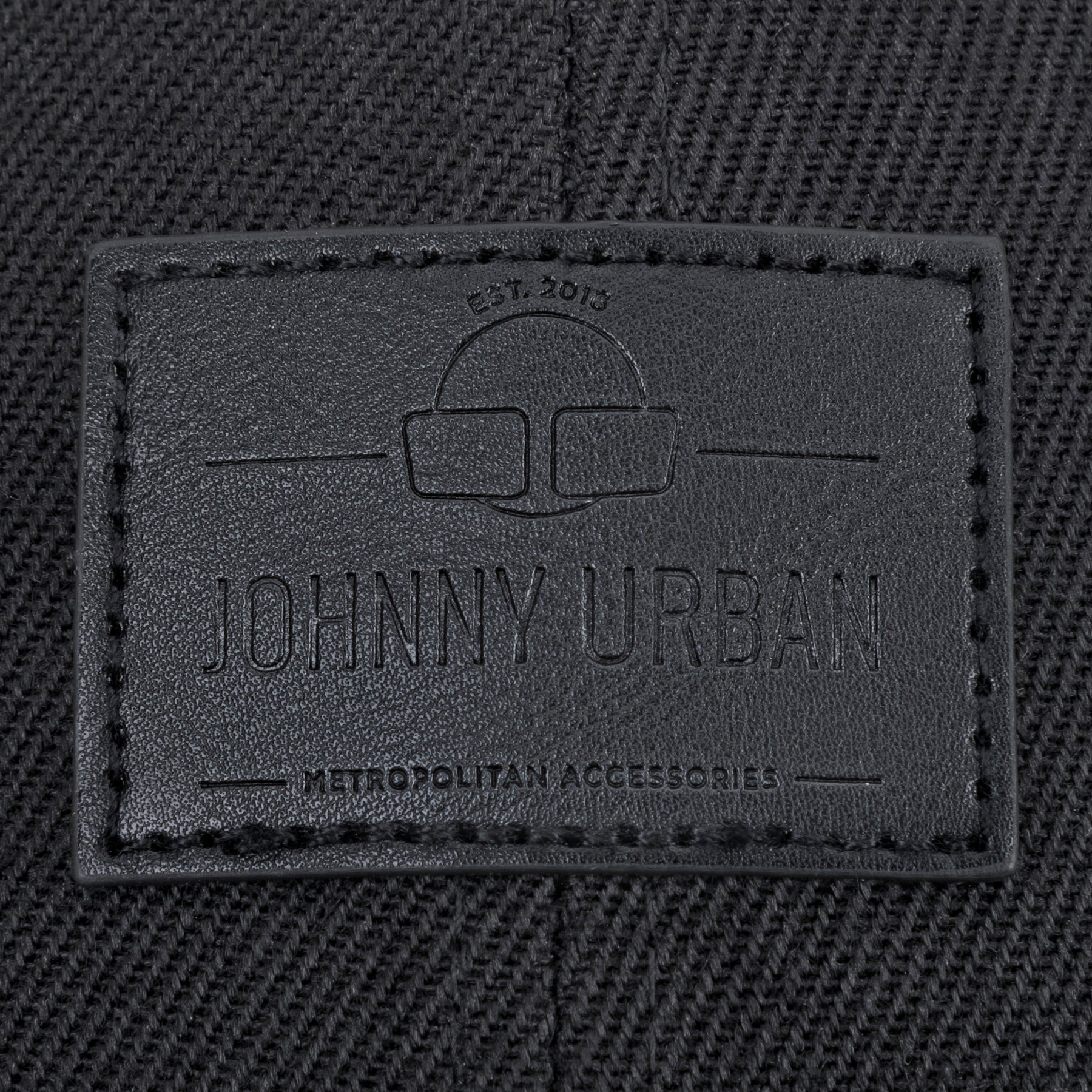 Schwarzes gewebtes Material mit Johnny Urban Lederetikett und eingraviertem Text 'Est. 2015', 'Johnny Urban', 'Metropolitan Accessories'