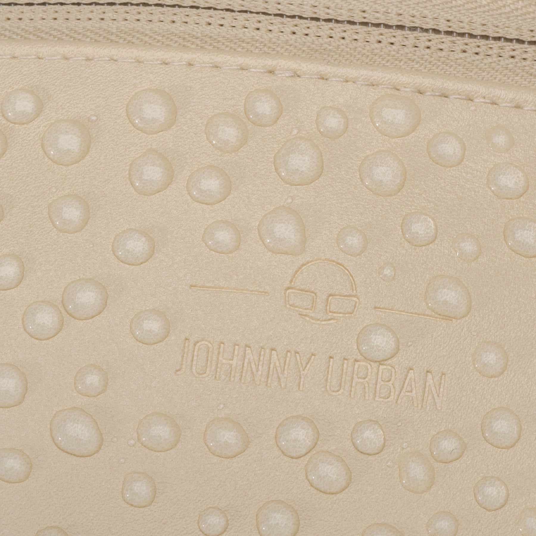 Nahaufnahme der wasserabweisenden, beigefarbenen Kunstleder-Oberfläche der Bauchtasche 'Toni' mit Johnny Urban Logo