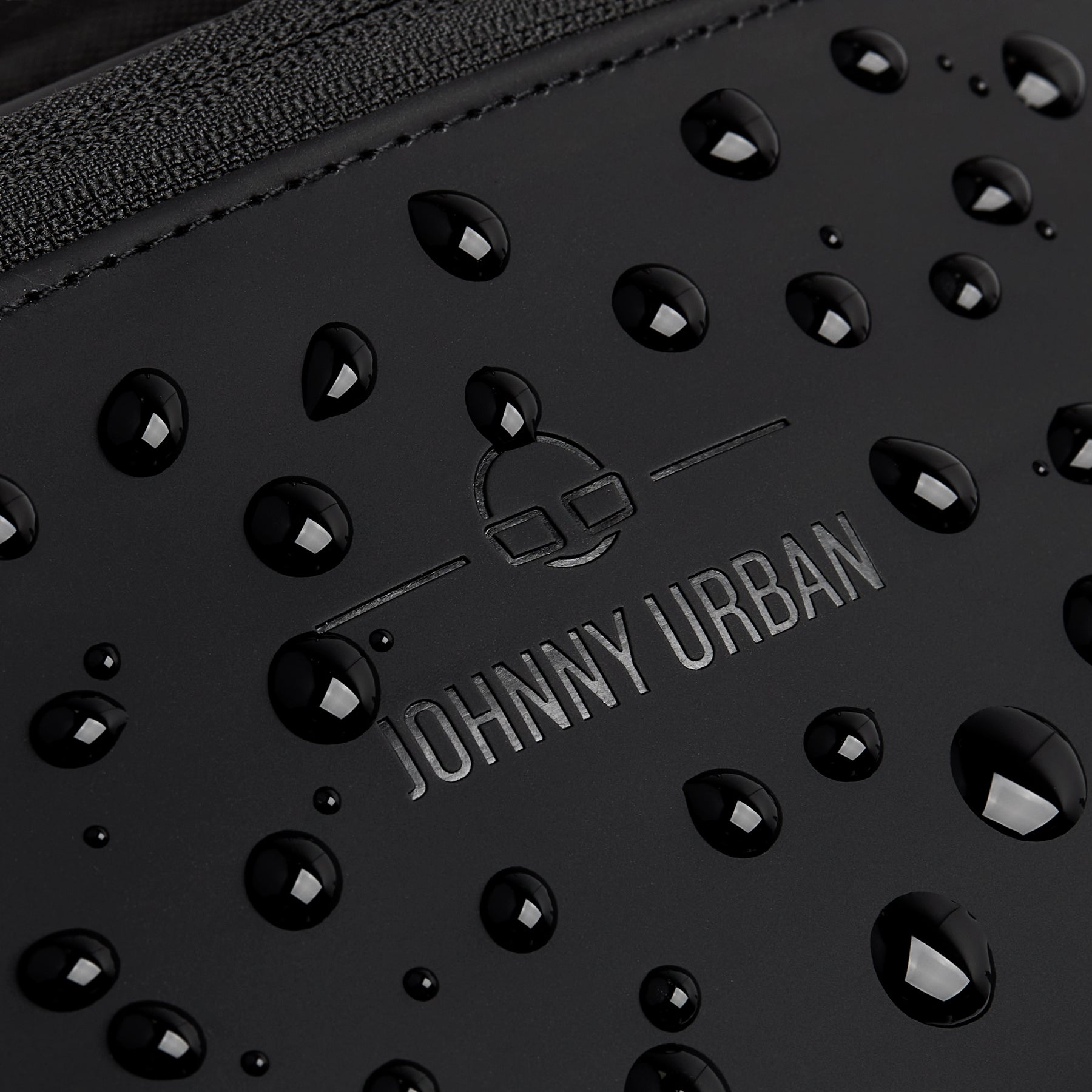 Nahaufnahme der wasserabweisenden Oberfläche der schwarzen Johnny Urban Bauchtasche 'Riley' mit Wassertröpfchen