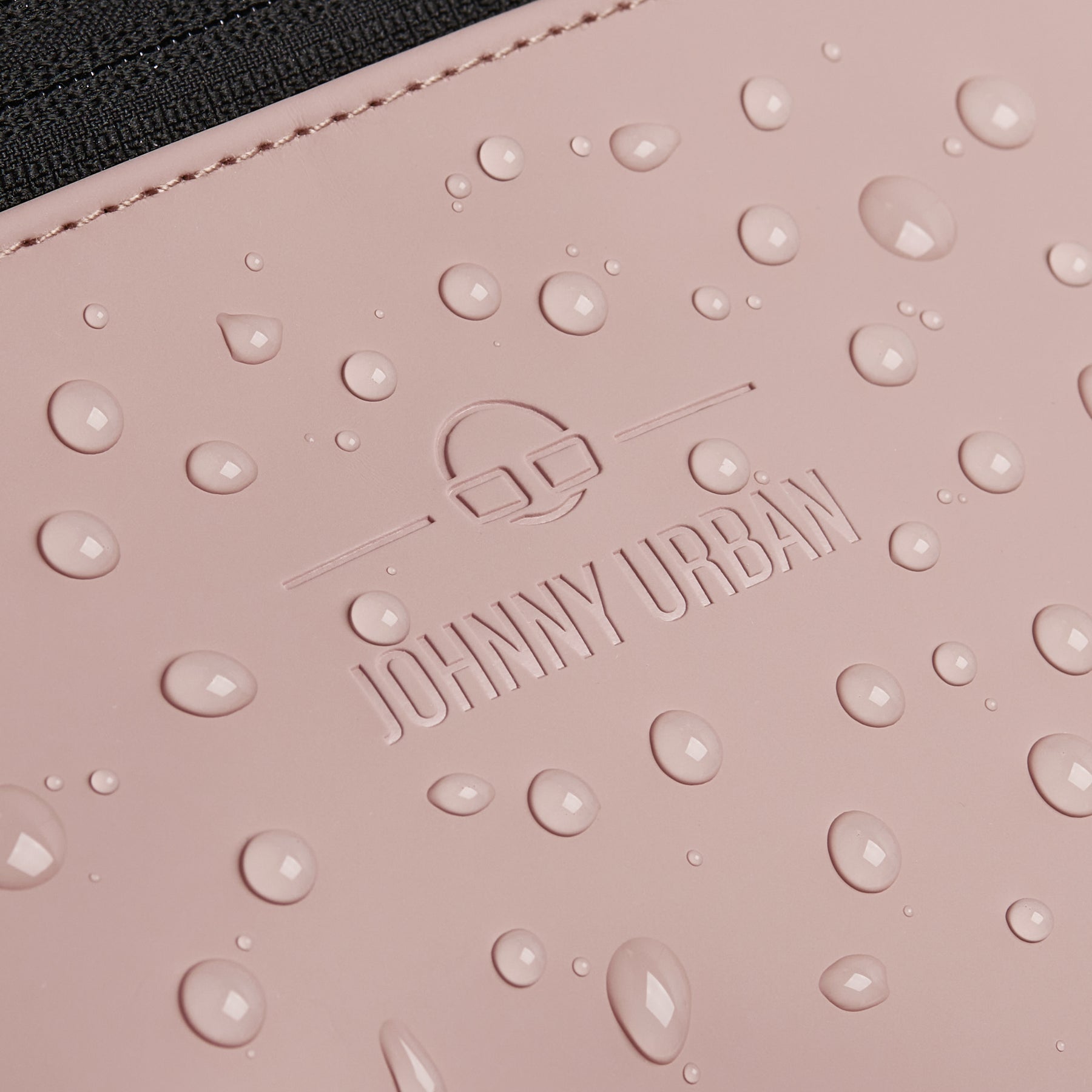 Nahaufnahme der rosa-grauen, wasserdichten Bauchtasche ‚Riley‘ von Johnny Urban mit Wassertropfen auf der Oberfläche