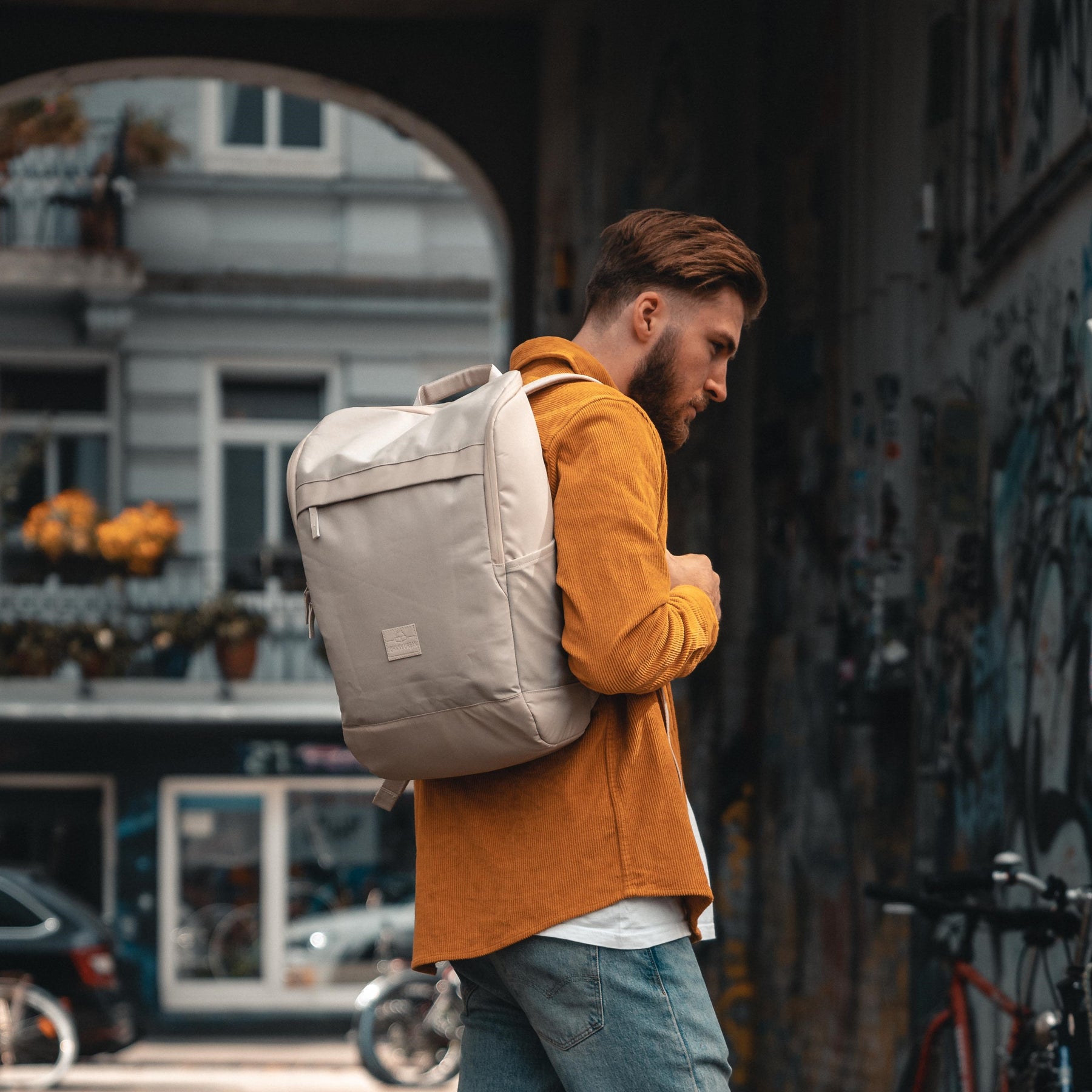 Mann trägt beigen Businessrucksack 'Jasper' von Johnny Urban, urbaner Hintergrund mit Graffiti