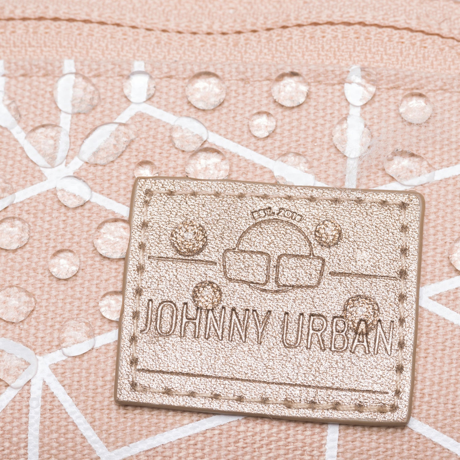 Nahe Ansicht einer rosafarbenen Johnny Urban Bauchtasche mit goldfarbenem Logo, das Wasserdropes abweist