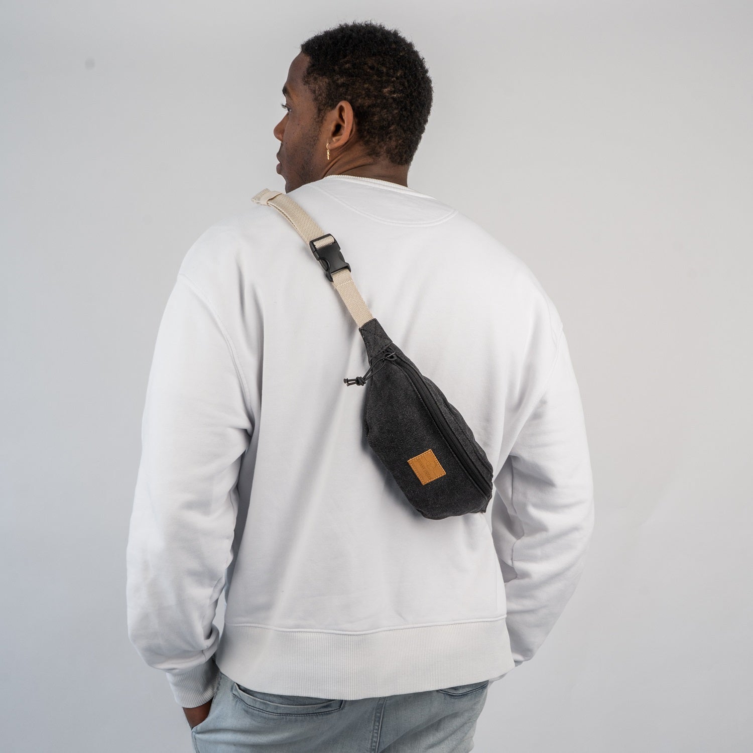 Mann trägt Bauchtasche 'Toni' von Johnny Urban in Anthrazit über der Schulter, weiße Sweatshirt