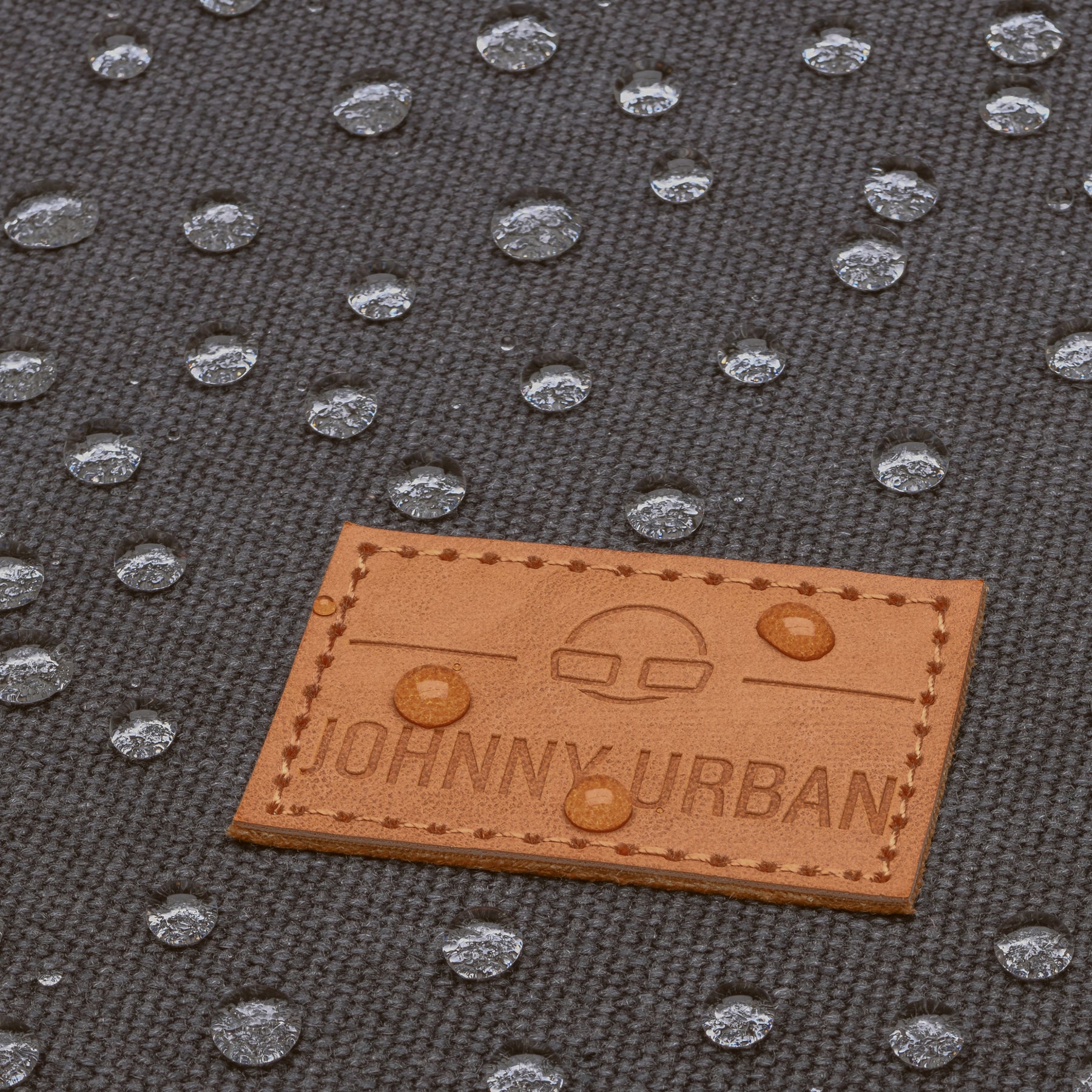 Wasserabweisendes Canvas-Material mit Johnny Urban Lederetikett und Wassertropfen