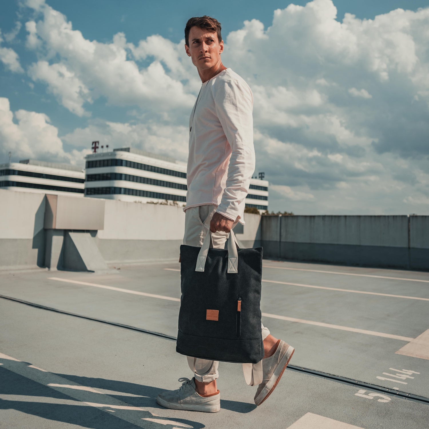 Mann trägt Rucksacktasche 'Sam' von Johnny Urban, anthrazitfarben aus Canvas, hält sie in der Hand