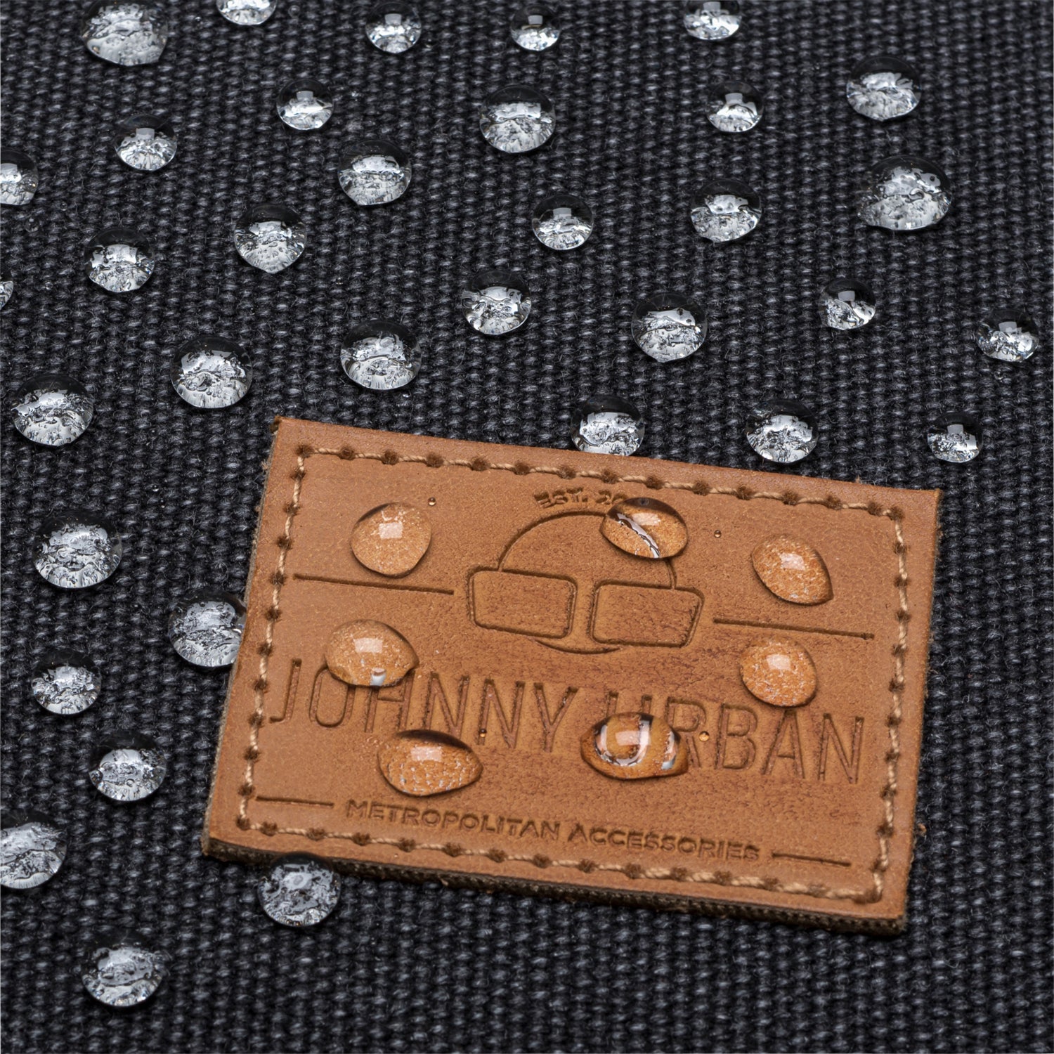 Wasserabweisender anthrazitfarbener Canvas-Stoff mit braunem JOHNNY URBAN Etikett und Wassertröpfchen