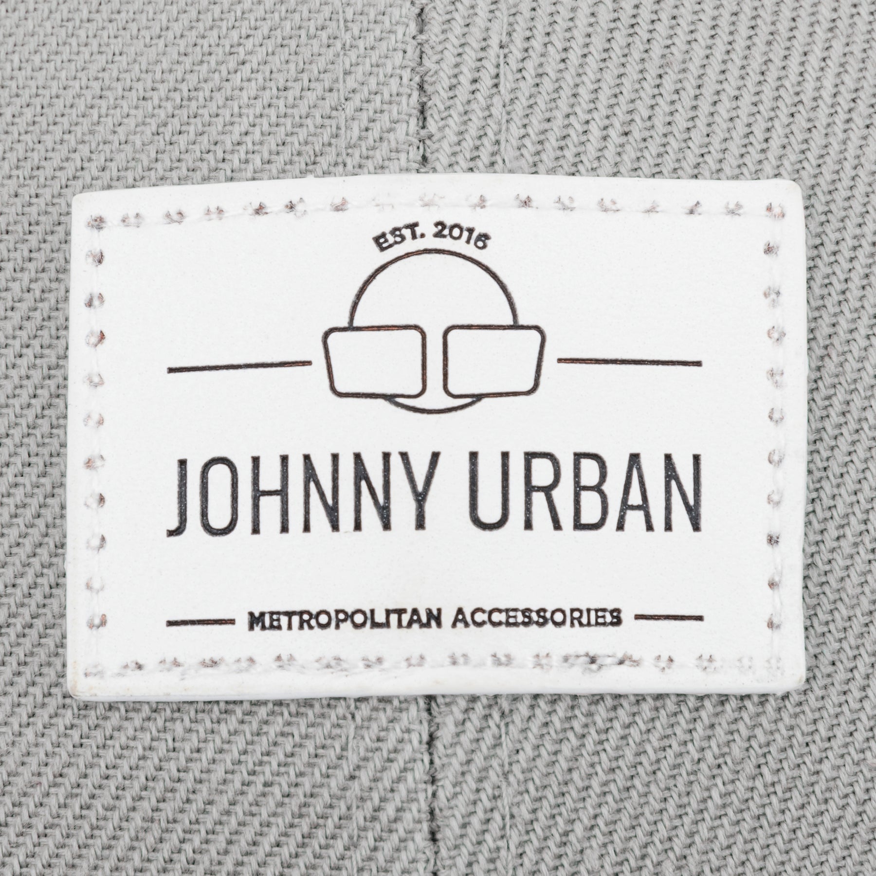 Label mit Logo und Text 'Johnny Urban Metropolitan Accessories EST. 2016' auf grauem Canvasstoff der Cap 'Dean' curved