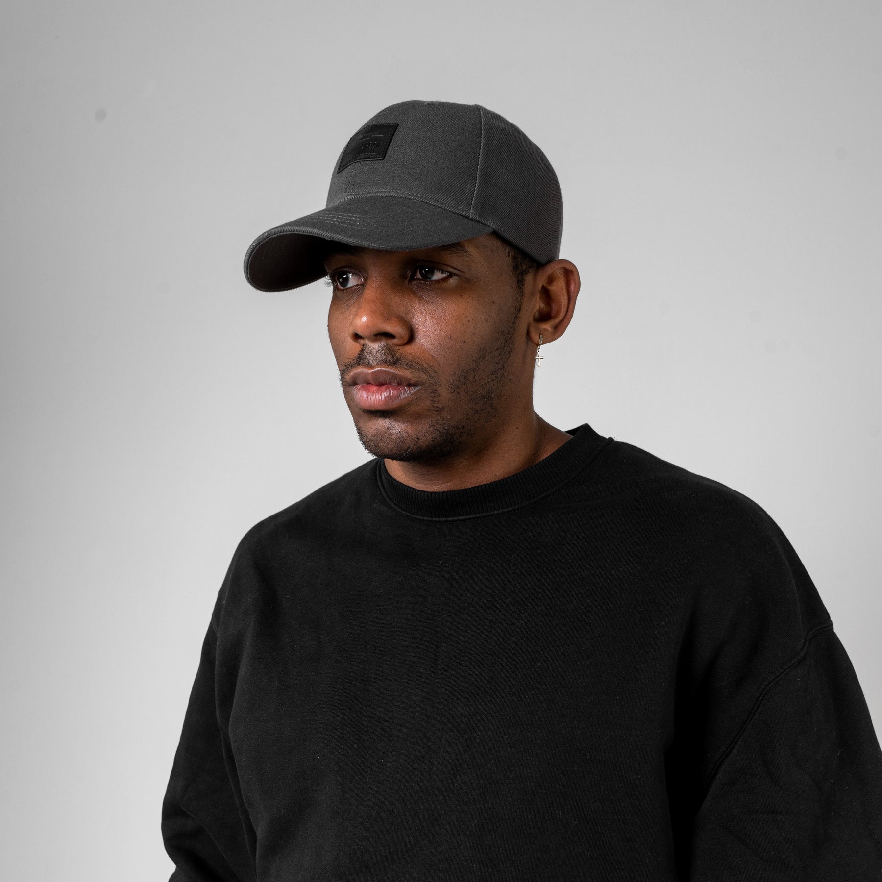 Mann trägt graue, gebogene Cap 'Dean' von Johnny Urban und schwarzen Pullover