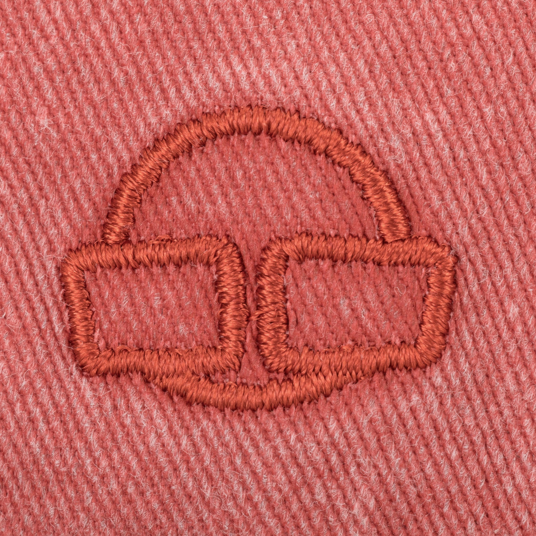 Nahaufnahme des roten Stickerei-Logos einer Kopfhörerform auf einem roten Stoff