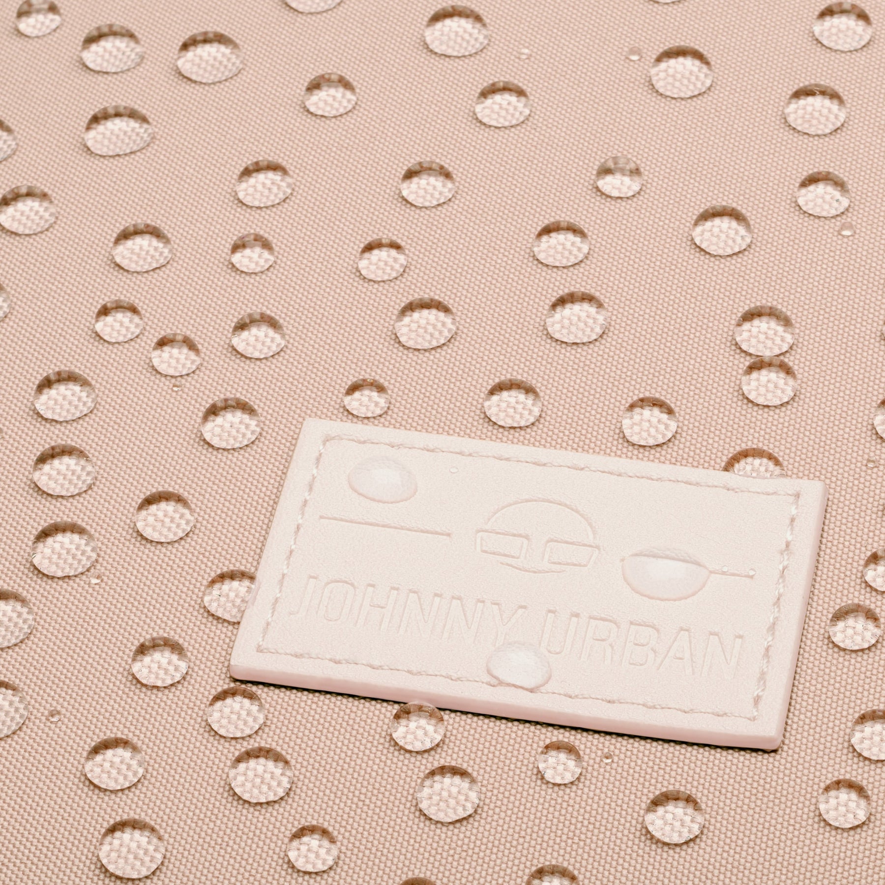 Nahaufnahme des rosafarbenen wasserabweisenden Stoffes des Johnny Urban Rucksacks 'Jona Medium' mit Wasserperlen.