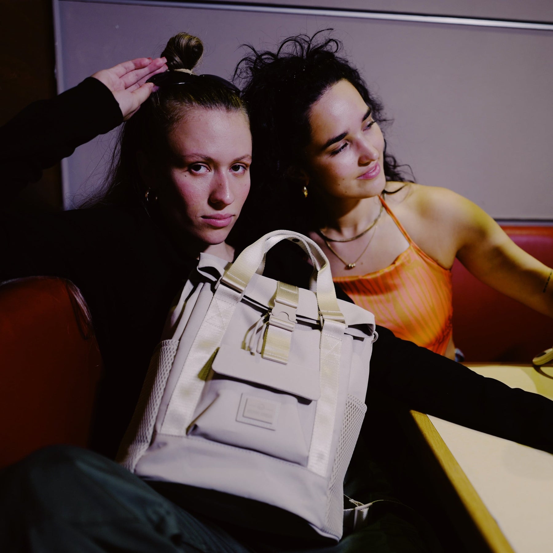 Zwei Frauen sitzen zusammen, eine trägt den beigen Rucksack 'Jules' von Johnny Urban auf dem Schoß