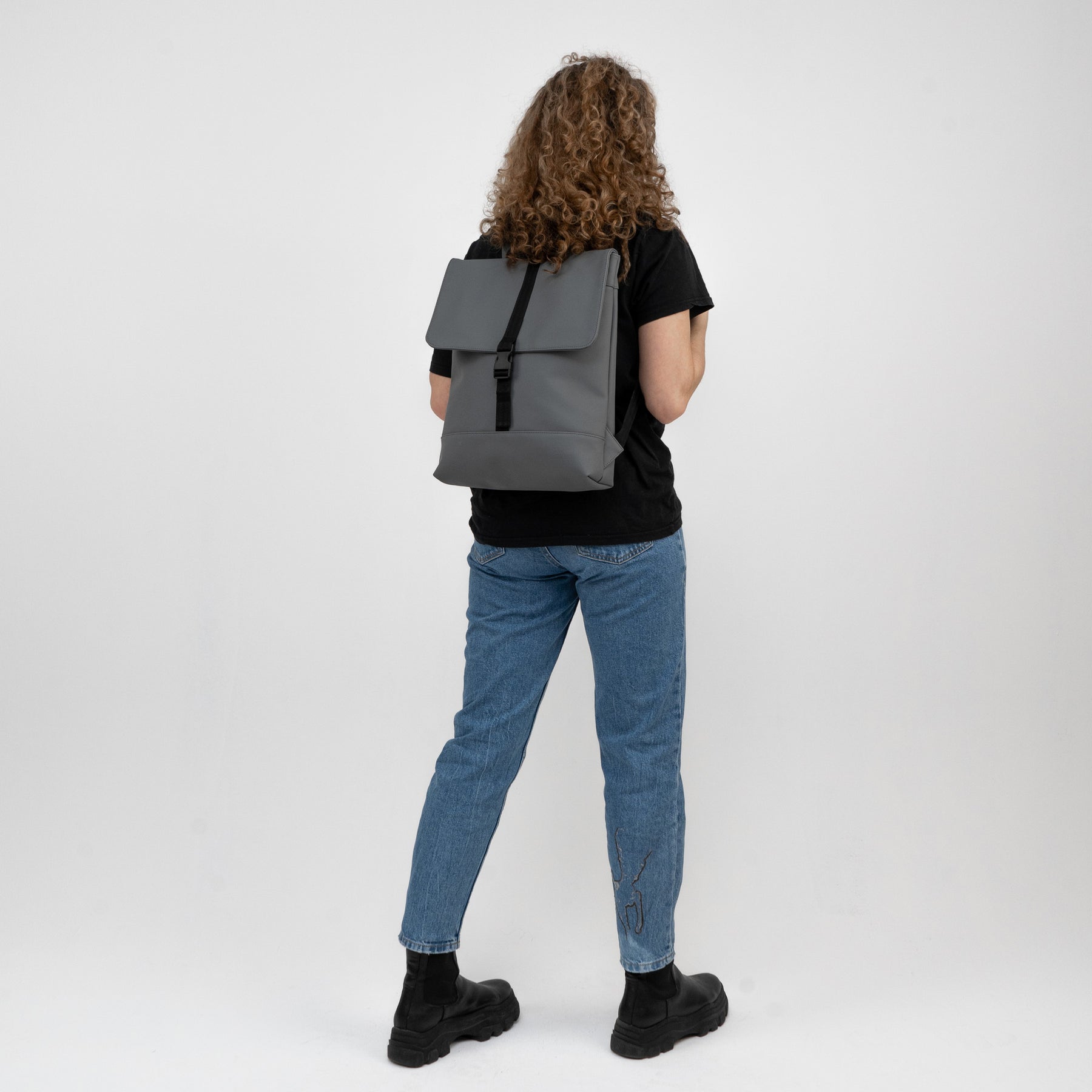 Frau trägt Damenrucksack 'Ruby' von Johnny Urban in Grau, einfache Klappe mit schwarzem Verschluss