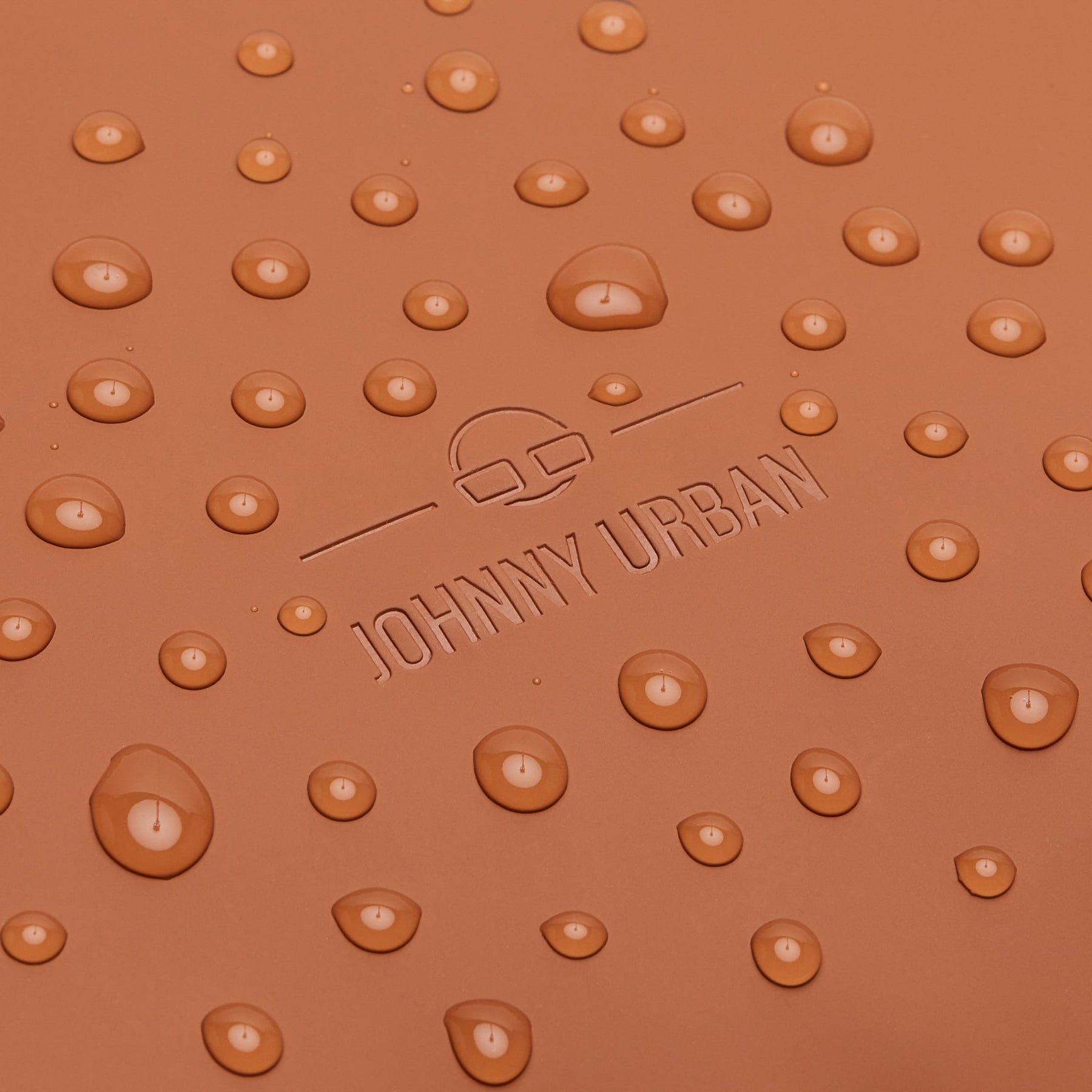 Nahaufnahme von wasserabweisendem Material mit eingeprägtem 'Johnny Urban' Logo und Wassertröpfchen