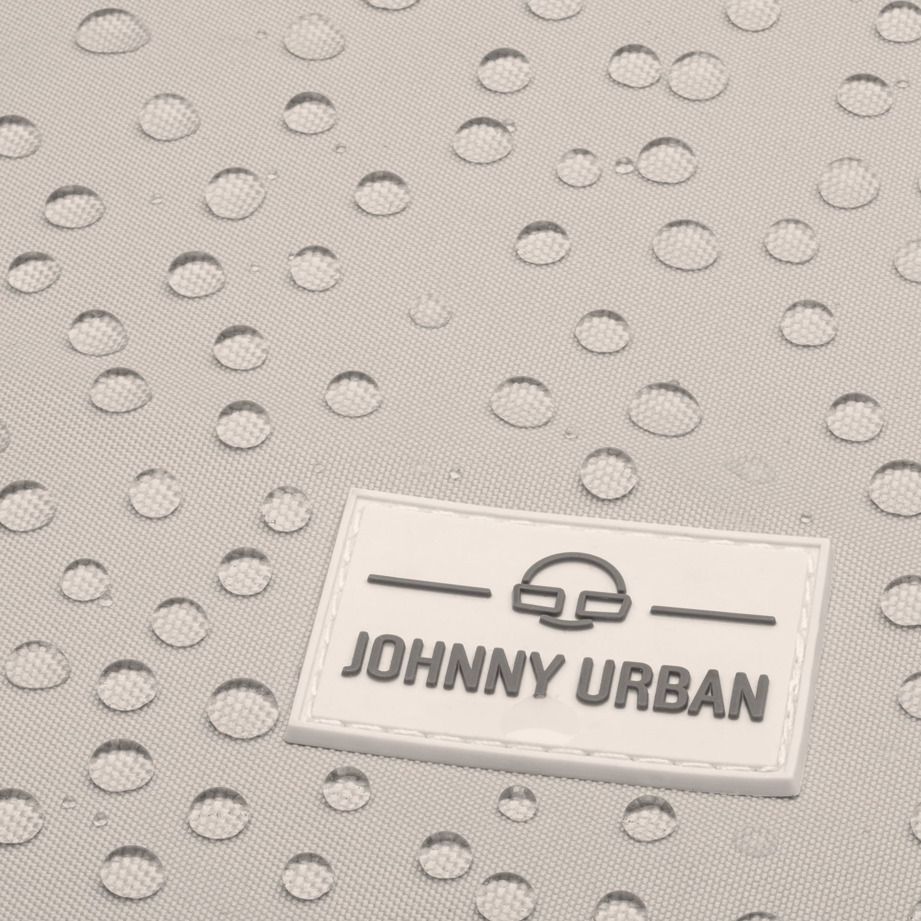 Detail des wasserabweisenden Jona Medium Rucksacks von Johnny Urban mit Wassertropfen auf beige-grauem Stoff