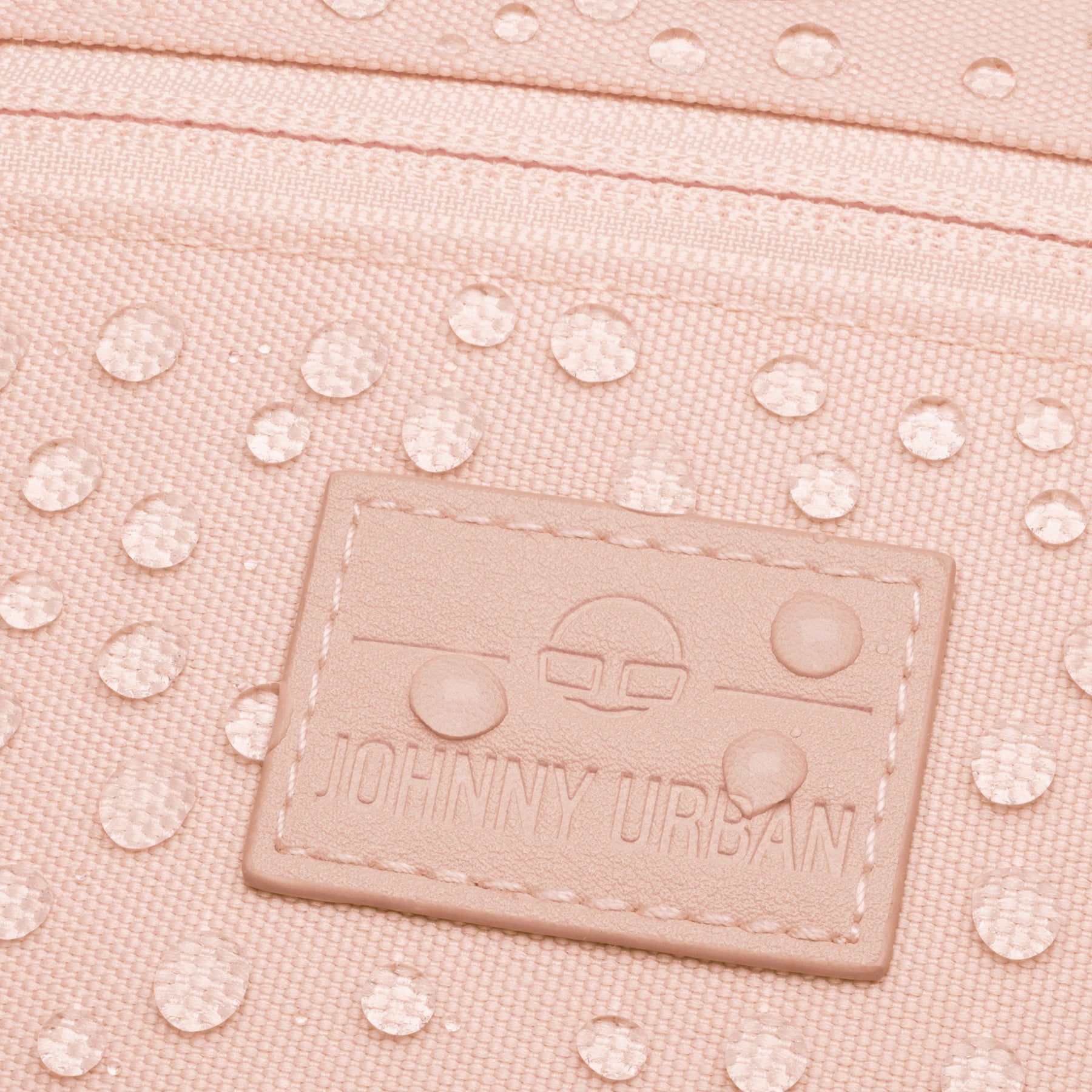 Nahaufnahme der rosa Bauchtasche 'Erik Small' mit Johnny Urban Logo und Wassertropfen auf der Oberfläche