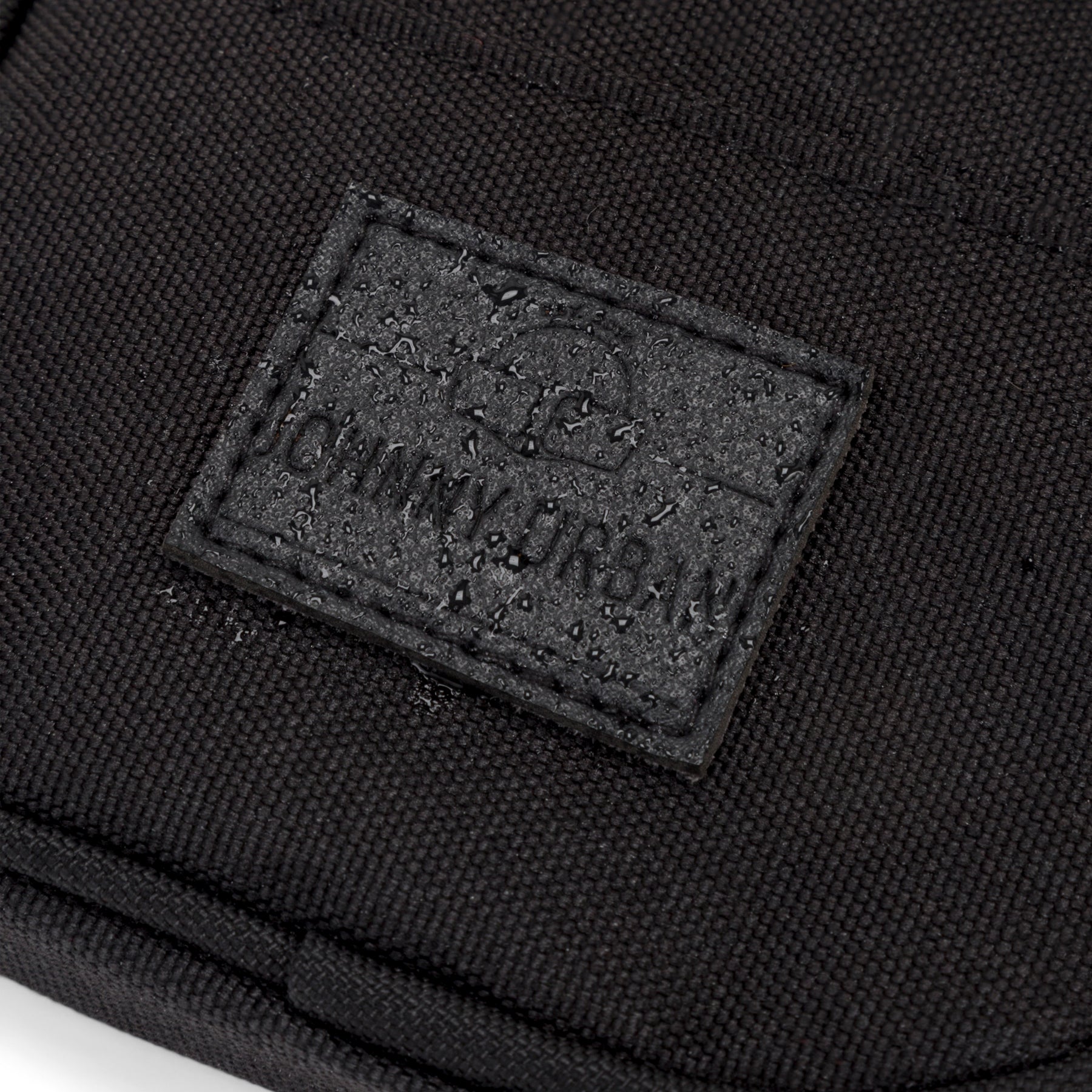 Wasserfester schwarzer Stoff mit Johnny Urban Markenetikett und Wassertropfen