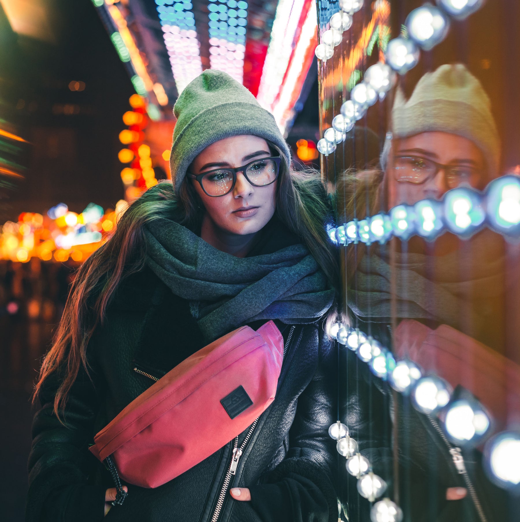 Frau mit Brille, grauer Mütze und Schal trägt rote Bauchtasche 'Tom' von Johnny Urban bei Nacht