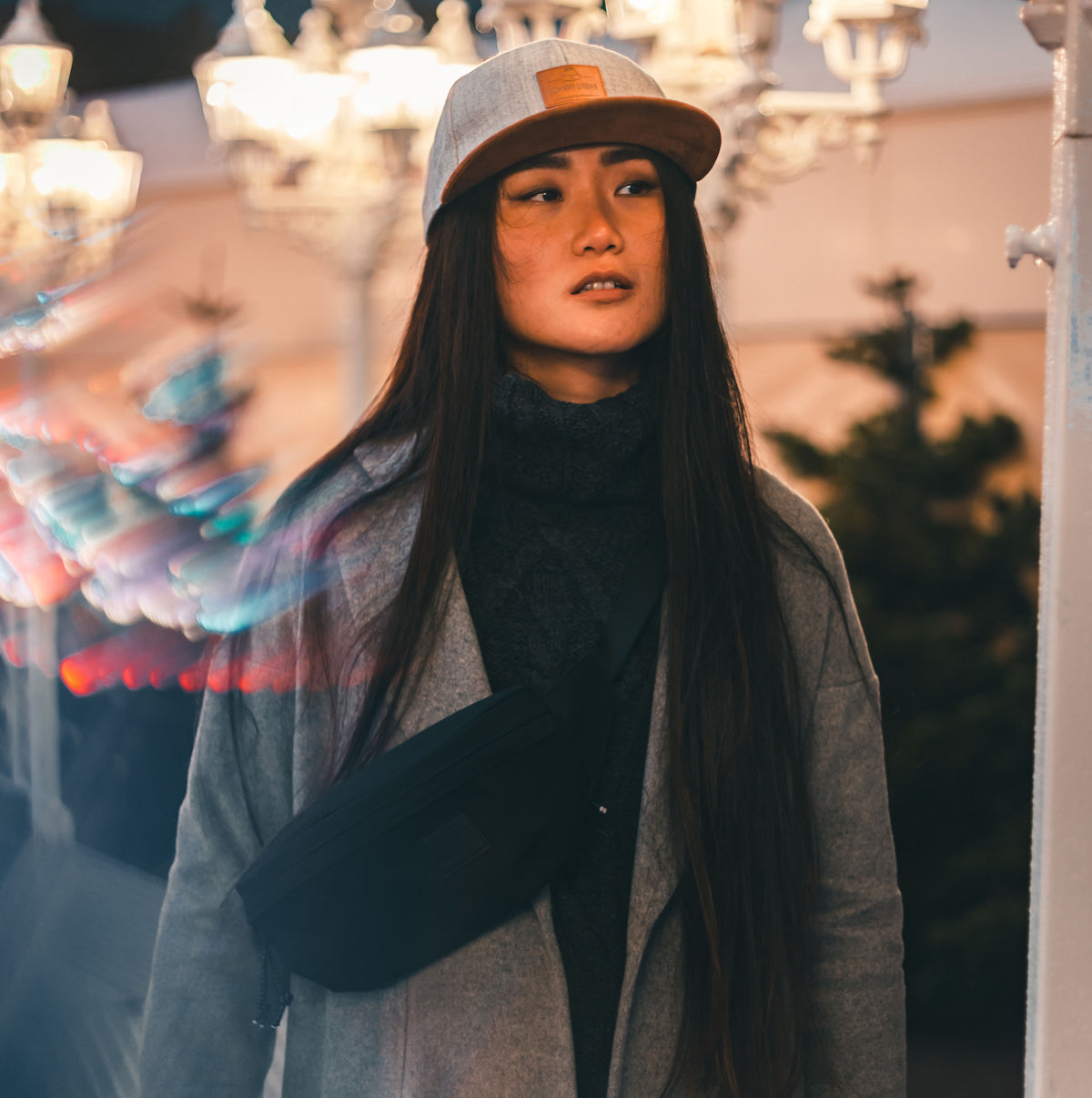 Frau mit langer Haaren, grauem Mantel, grauer Kappe und schwarzer Bauchtasche 'Tom' von Johnny Urban