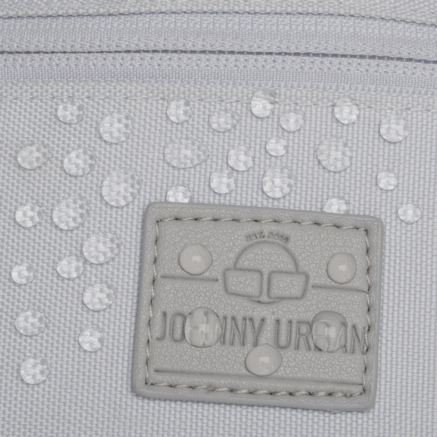 Nahaufnahme des wasserabweisenden Materials und des Logos der grauen Bauchtasche 'Erik Small' von Johnny Urban