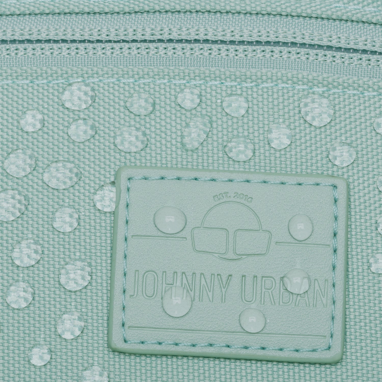 Mintgrüne, wasserabweisende Bauchtasche 'Erik Small' von Johnny Urban mit Logoetikett und Wassertropfen auf dem Material