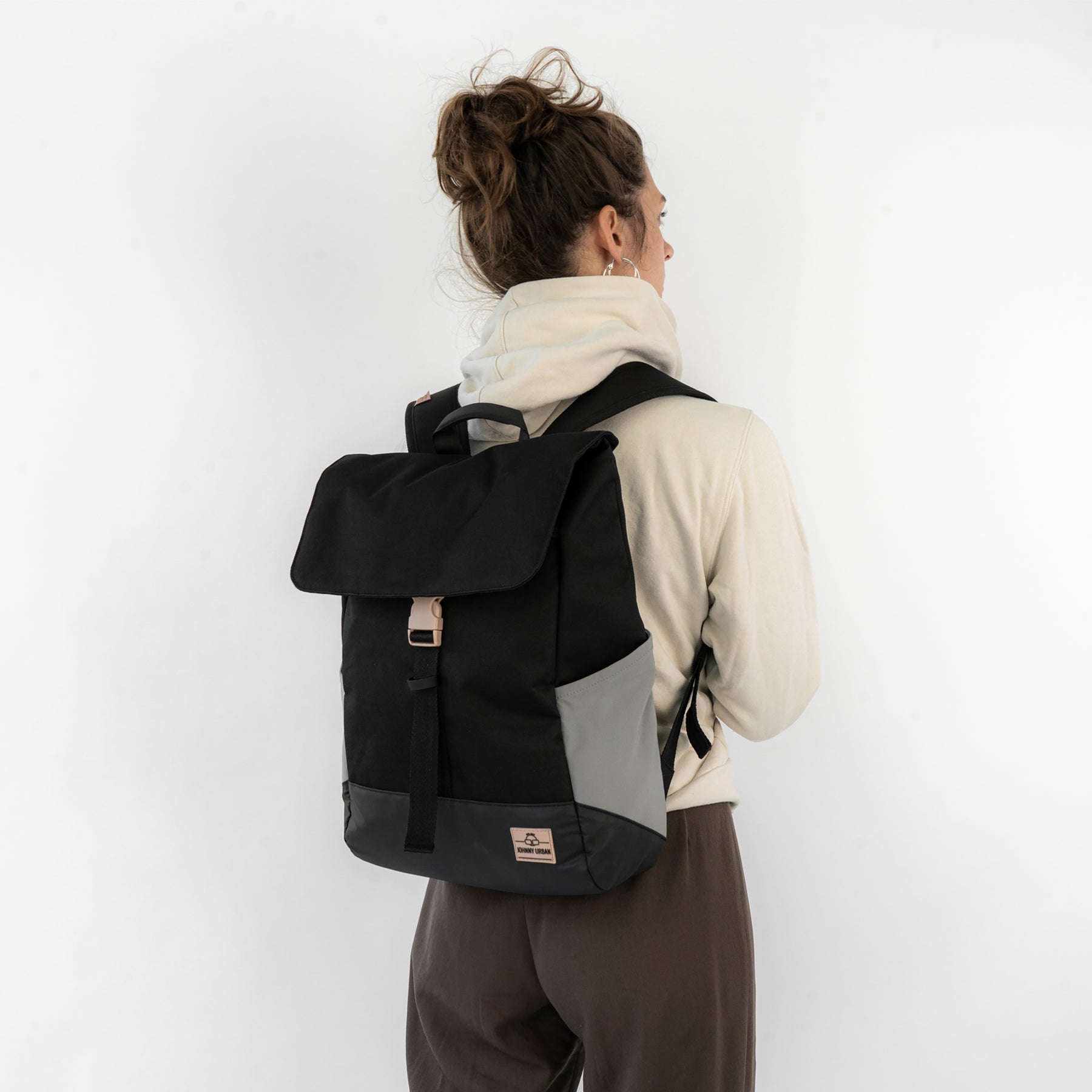 Rucksack 'Mika' von Johnny Urban in Schwarz mit grauen Details, getragen von einer Frau mit beigem Pullover und braunen Hosen