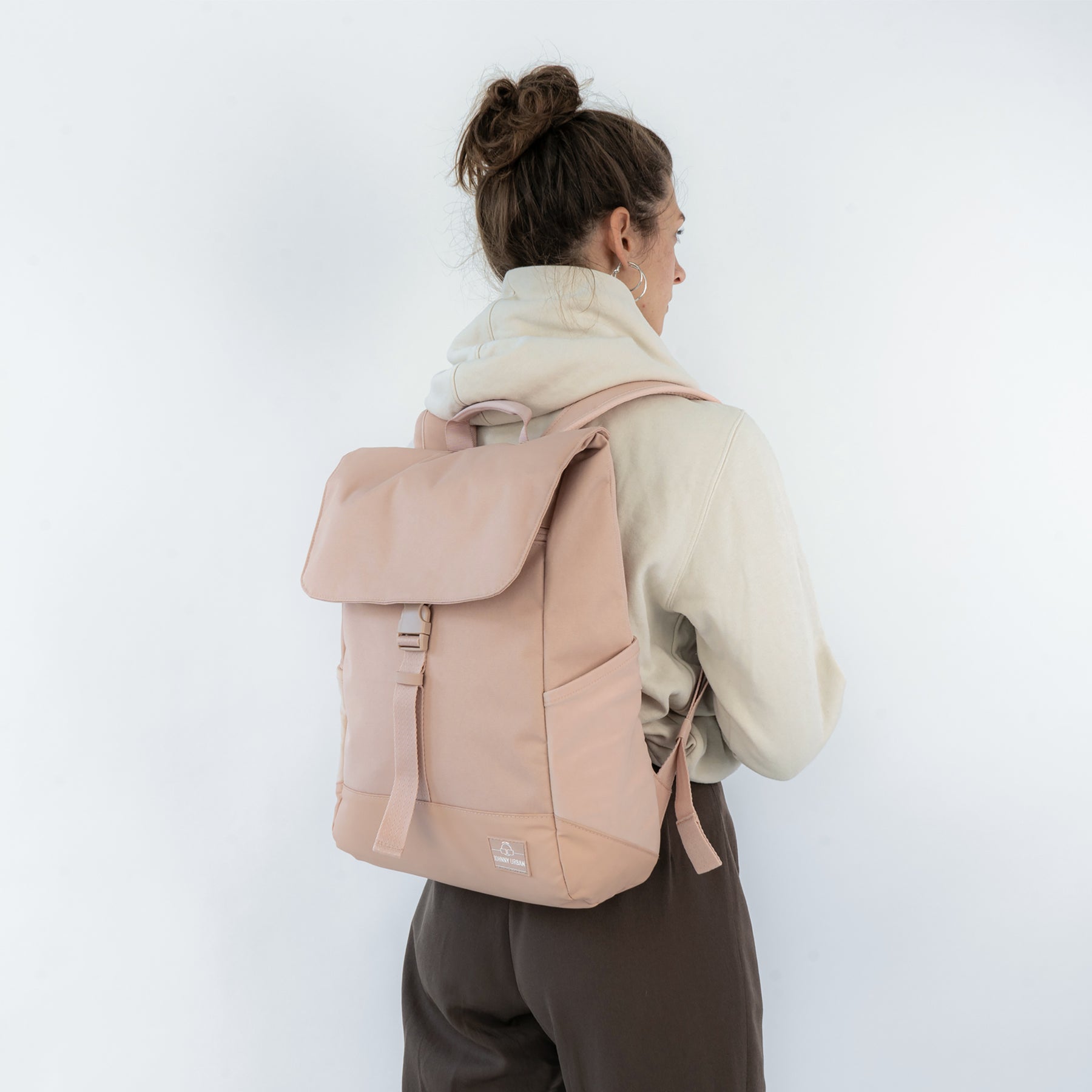 Frau von hinten mit beigem Rucksack 'Mika' und hellem Hoodie, braune Hose