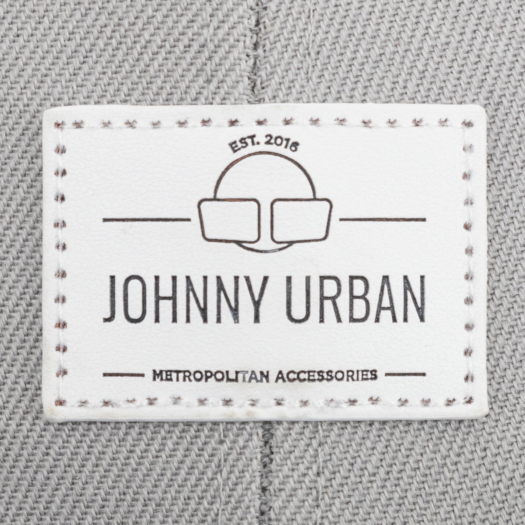 Johnny Urban Logoetikett mit 'EST. 2016' und 'METROPOLITAN ACCESSORIES' auf grauem Stoff