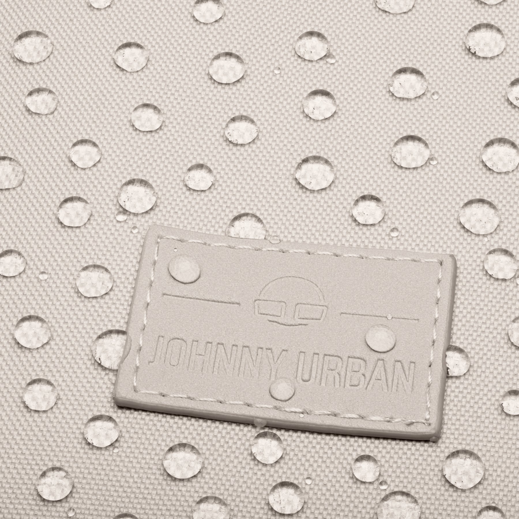 Nahe Nahaufnahme des wasserdichten Materials des Johnny Urban Rolltop Rucksacks "Robin Medium" mit aufgenähtem Logo