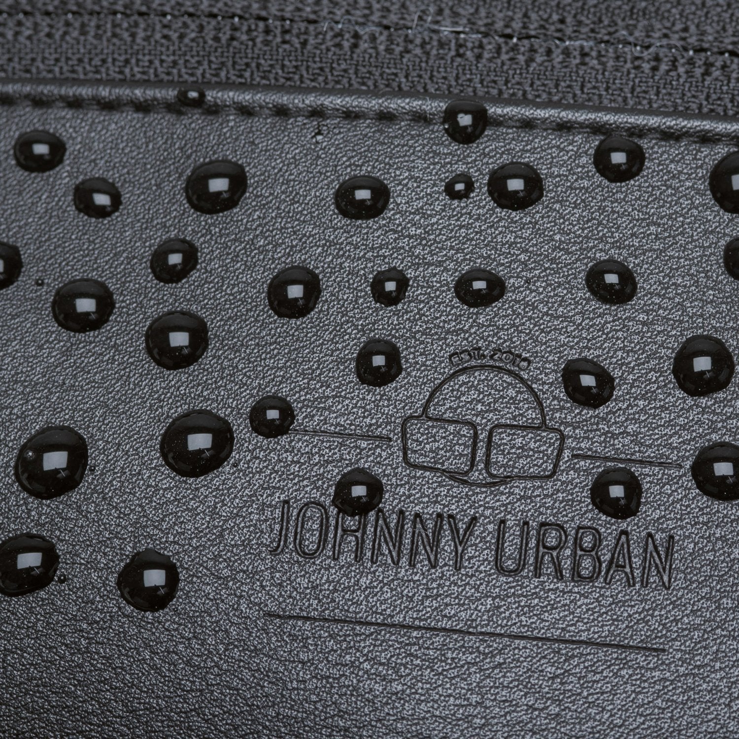Nahaufnahme der wasserabweisenden schwarzen Kunstleder-Bauchtasche 'Toni' von Johnny Urban mit Wasserperlen auf der Oberfläche