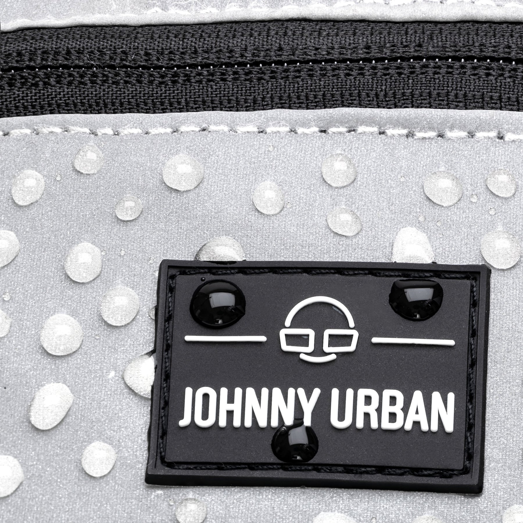 Nahaufnahme der reflektierenden, wasserabweisenden Bauchtasche ‚Erik Small‘ von Johnny Urban mit Logo und Wasserperlen