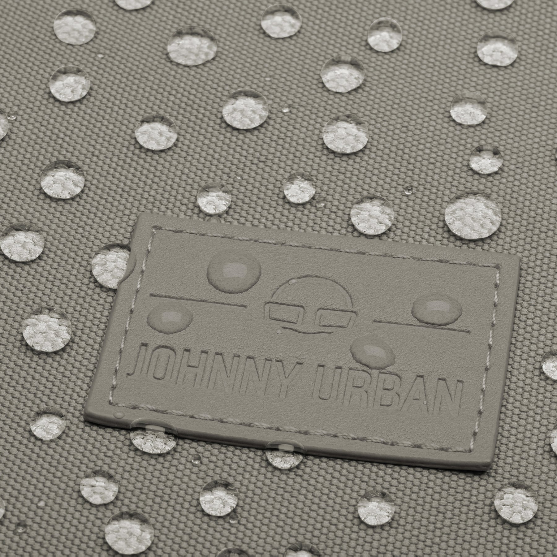 Logo von Johnny Urban auf dem wasserabweisenden Stoff des Rolltop Rucksacks Robin Medium in desert grey