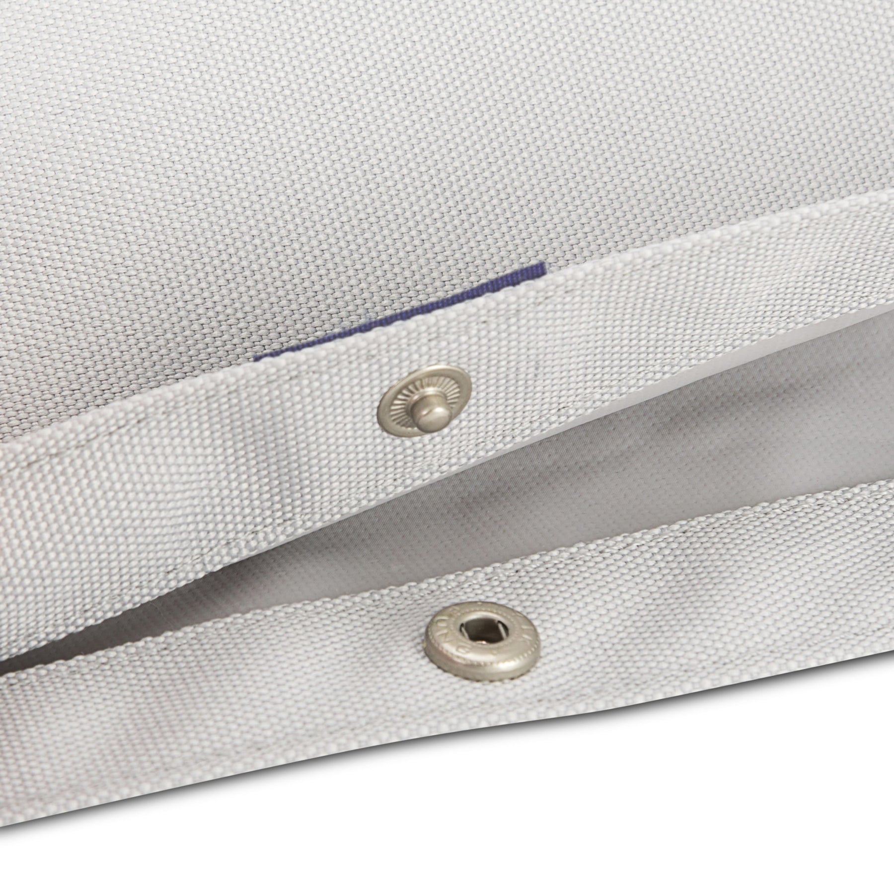 Nahaufnahme des hellgrauen Textilstoffs und Metall-Druckknopfverschlusses des Rolltop Kinderrucksacks 'Aaron'